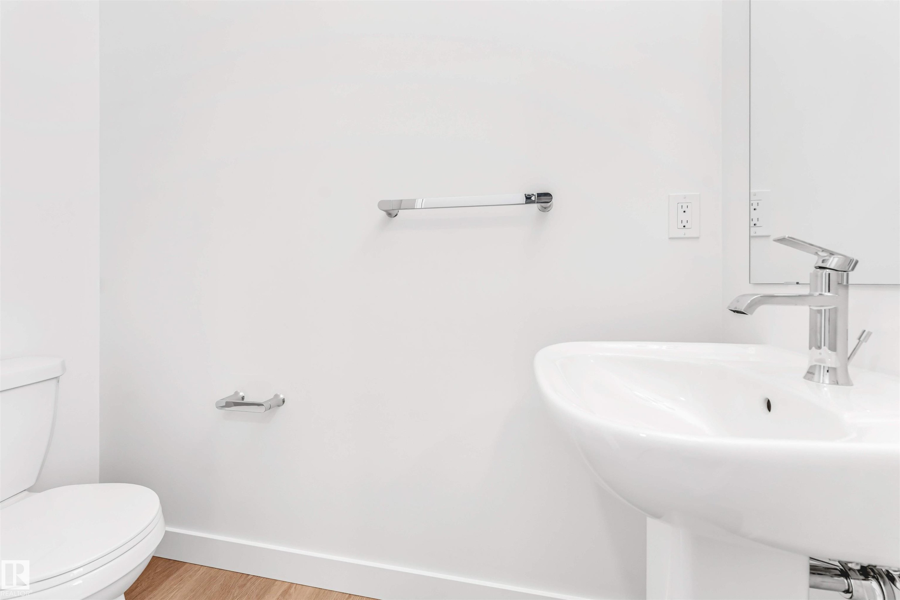 Pedestal sink with chrome faucet, complemented by a white toilet and wood-finish flooring - #48 710 Mattson Dr Sw Sw, Edmonton, AB