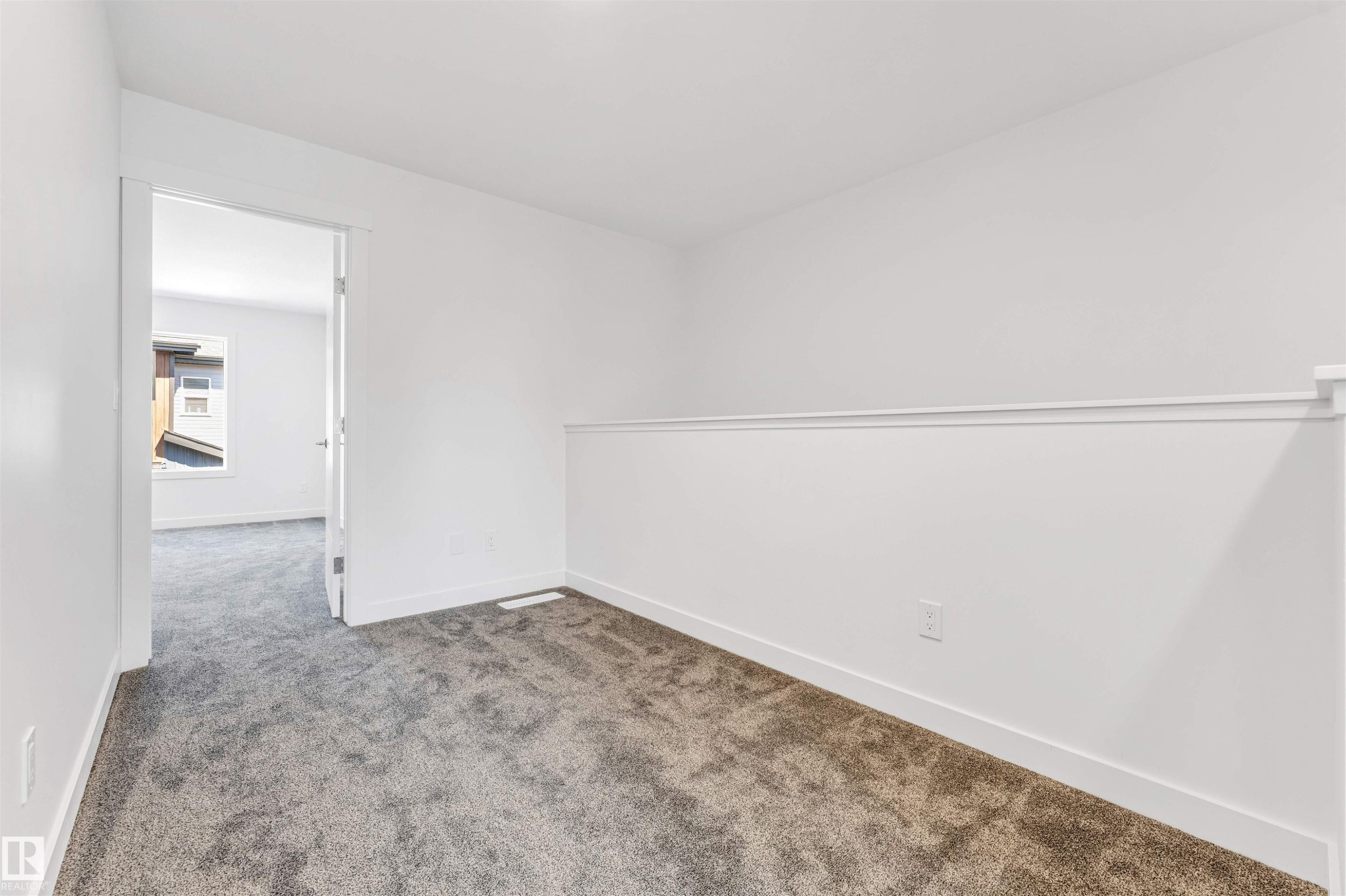 Bright secondary bedroom featuring neutral wall finishes, carpet flooring, and an open floor plan with direct access to adjoining spaces - #48 710 Mattson Dr Sw Sw, Edmonton, AB