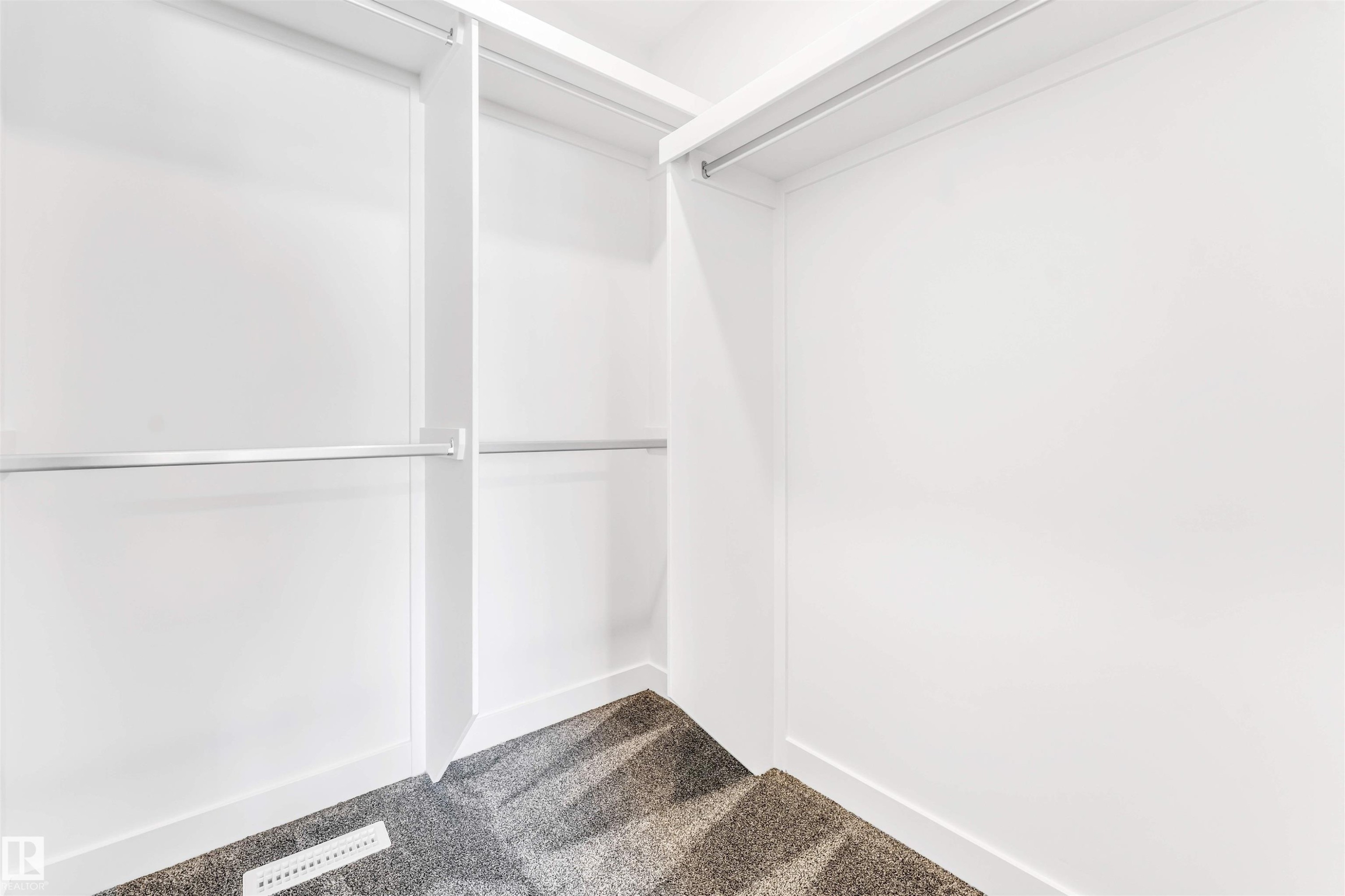 Walk-in closet with multiple hanging rods, white shelving, and grey carpeting - #48 710 Mattson Dr Sw Sw, Edmonton, AB