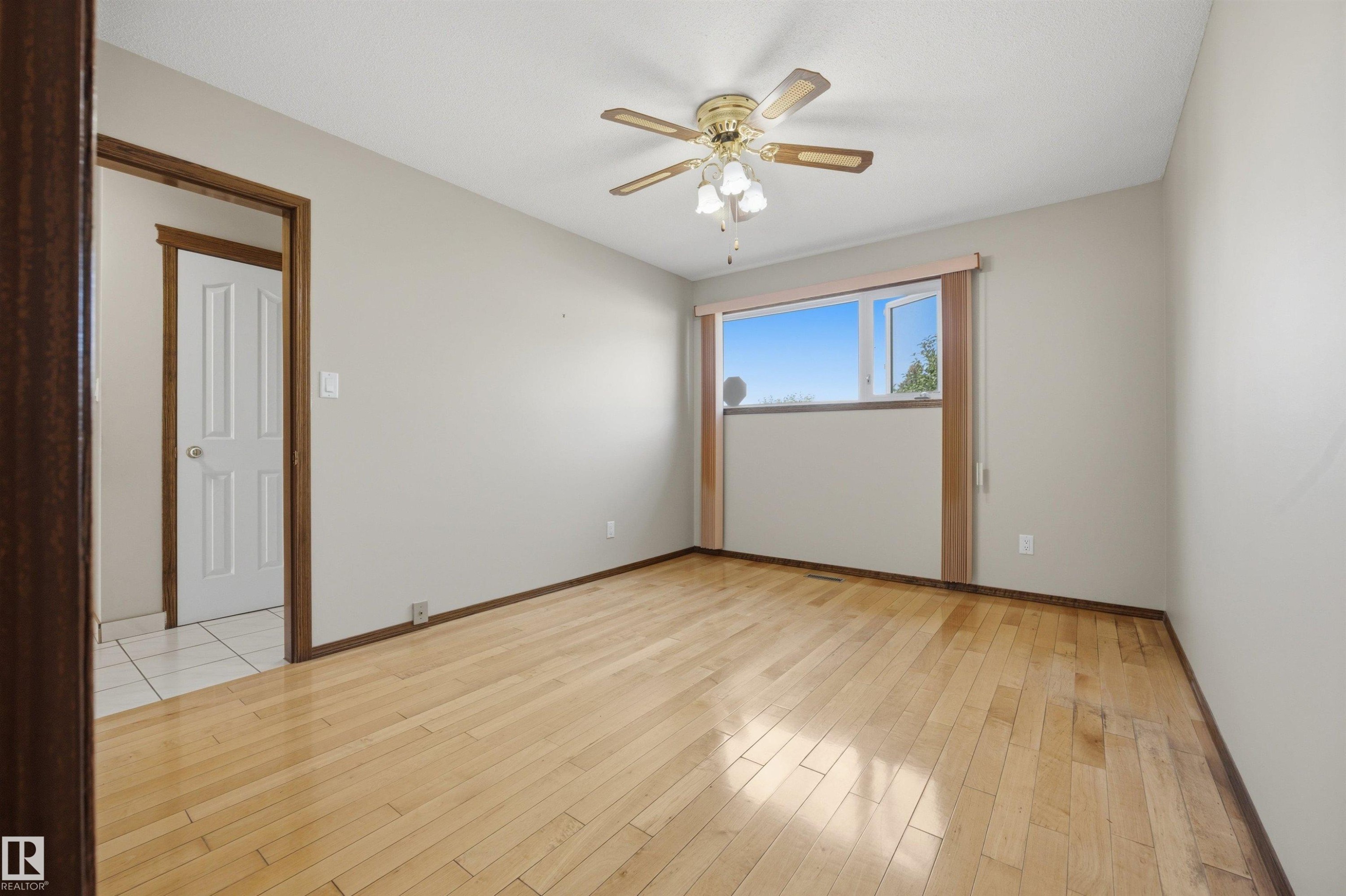 Light wood-finish flooring, a ceiling fan with integrated lighting, and a window with a light-colored frame - 14008 94 Street Nw, Edmonton, AB