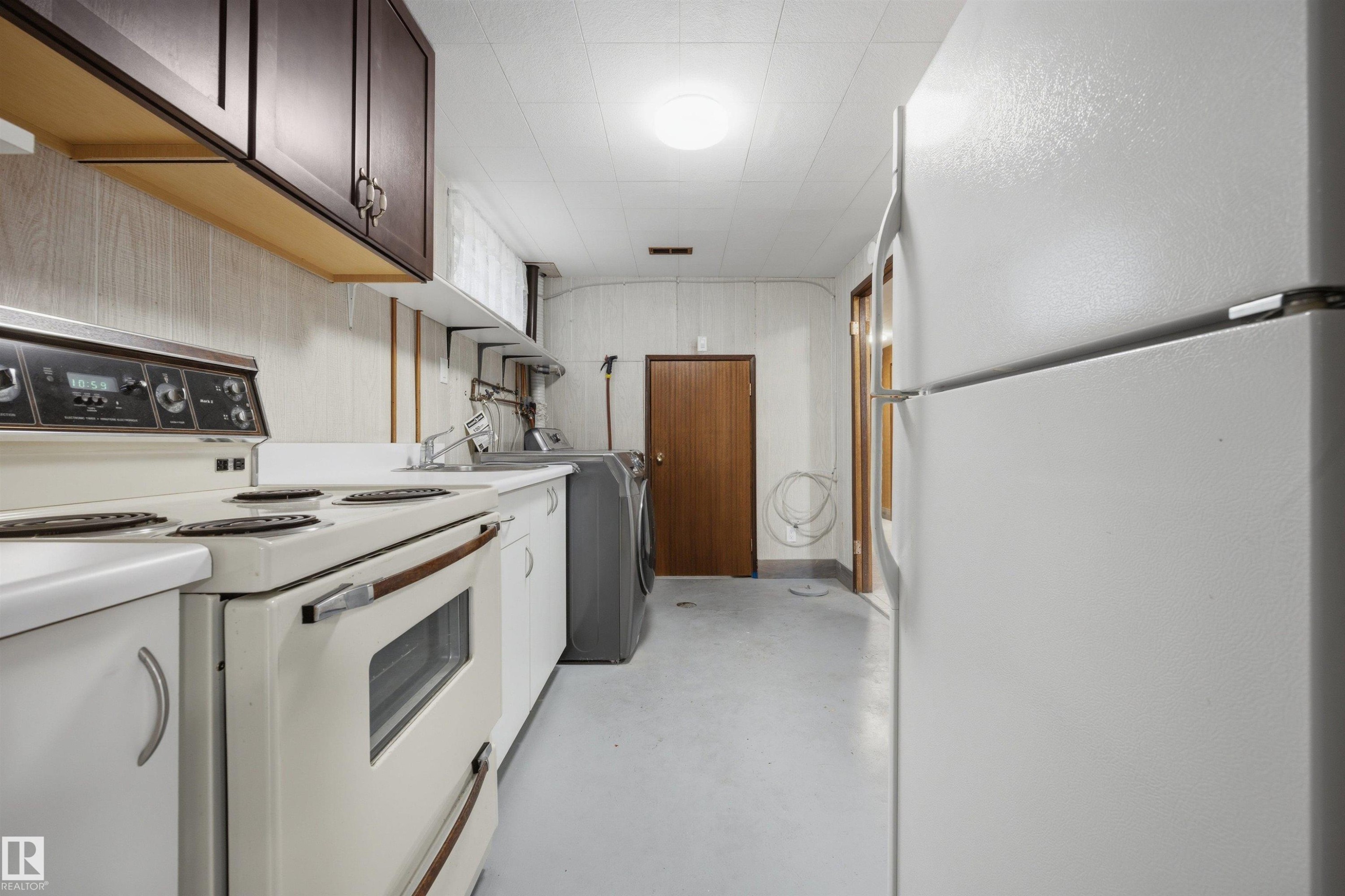 Functional kitchen space featuring white appliances, a top-mount sink, and dark wood-finish cabinetry - 14008 94 Street Nw, Edmonton, AB