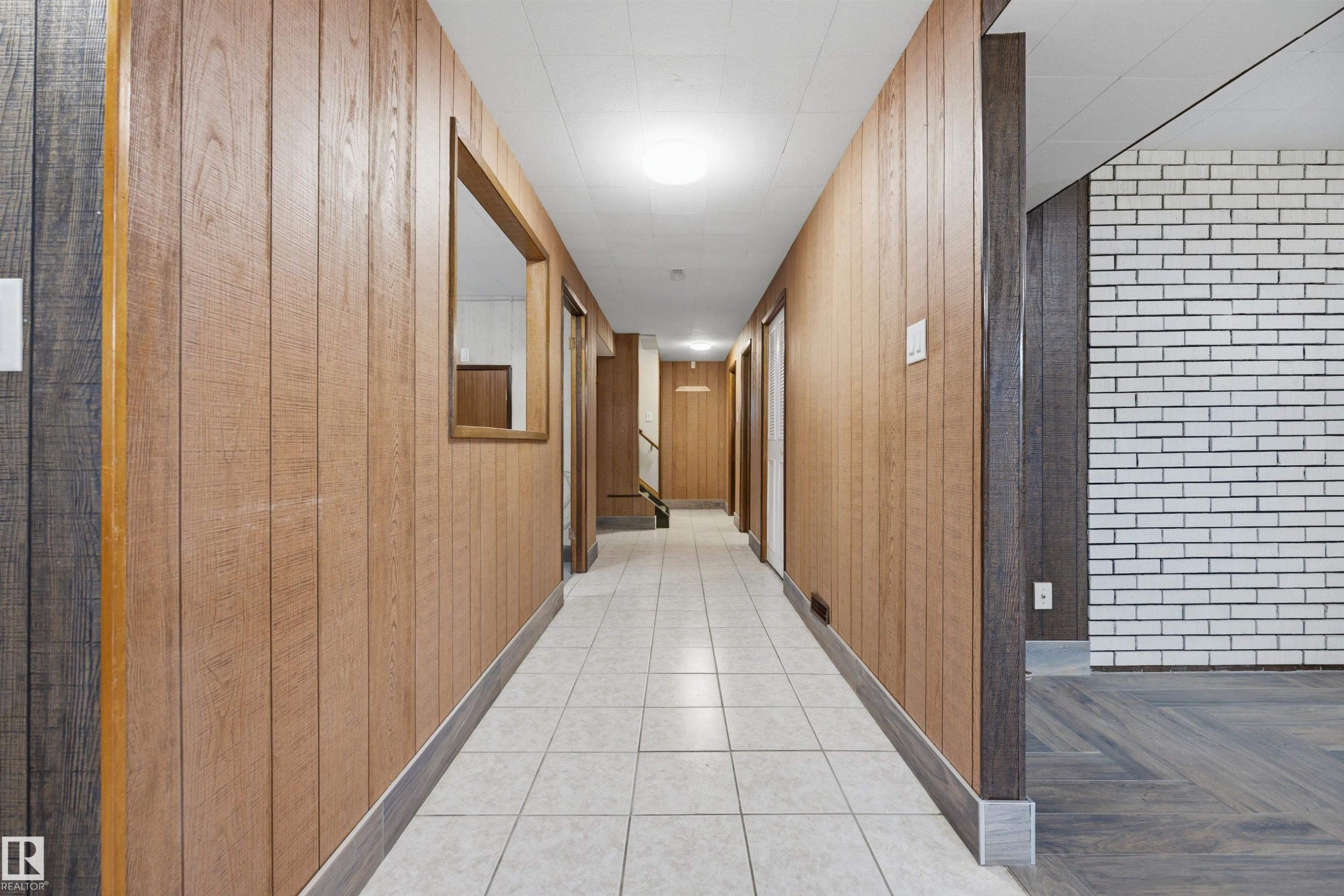 Hallway with wood-finish paneling, white ceramic tile flooring, and a window opening - 14008 94 Street Nw, Edmonton, AB