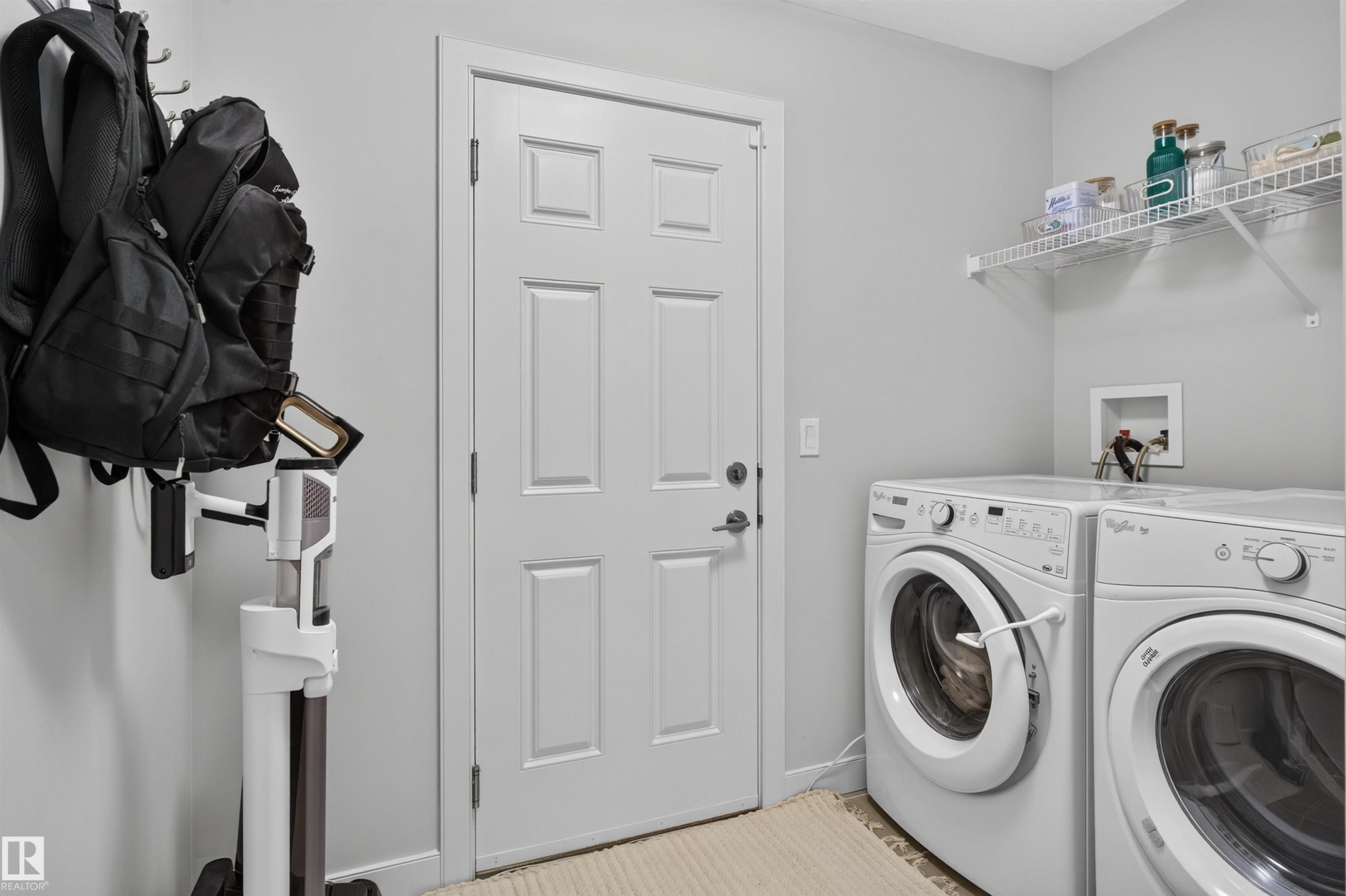 Utility area featuring a paneled door, wall-mounted wire shelving, and appliance hookups - 5130 Godson Close Nw, Edmonton, AB