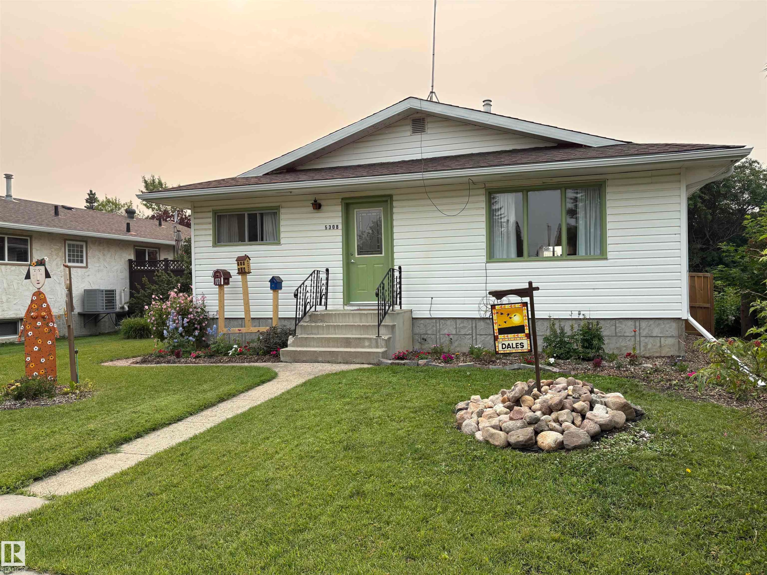 White siding residence with a vibrant green entry door and coordinating window trim - 5308 50 St, Ryley, AB