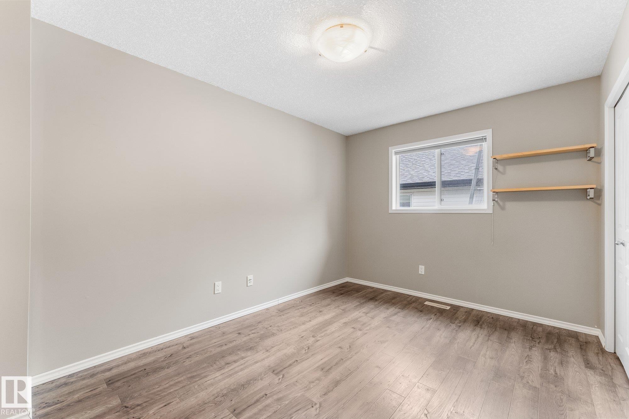Wood-finish flooring, neutral wall paint, and a textured ceiling - 2060 Brennan Crescent Nw, Edmonton, AB