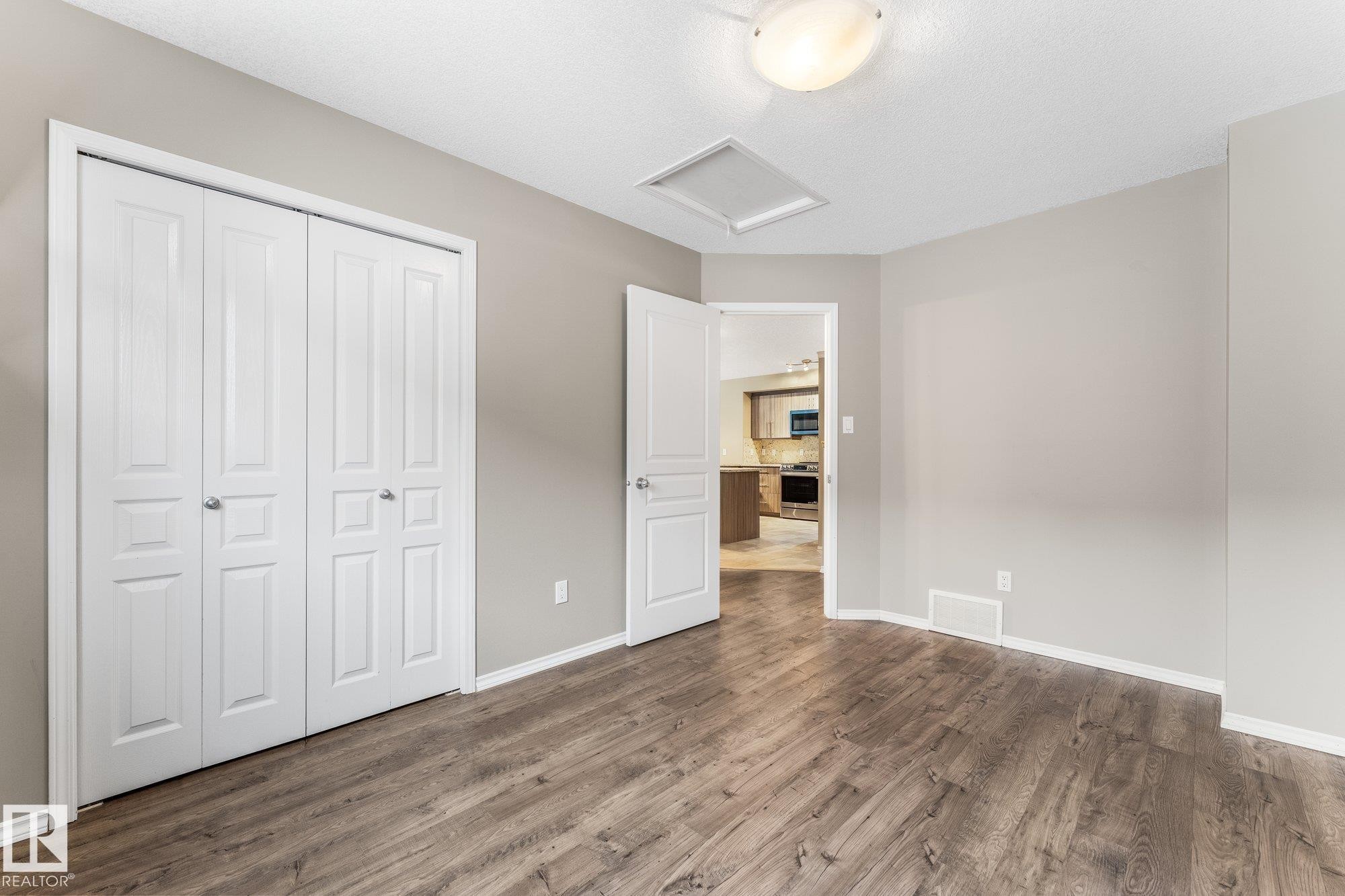 Wood-finish flooring throughout, complemented by light-toned wall paint and white trim - 2060 Brennan Crescent Nw, Edmonton, AB