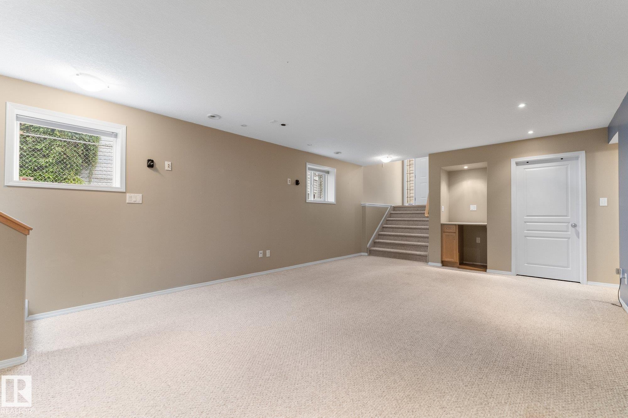 Carpeted living area with recessed lighting, built-in cabinetry, and a window with blinds - 2060 Brennan Crescent Nw, Edmonton, AB