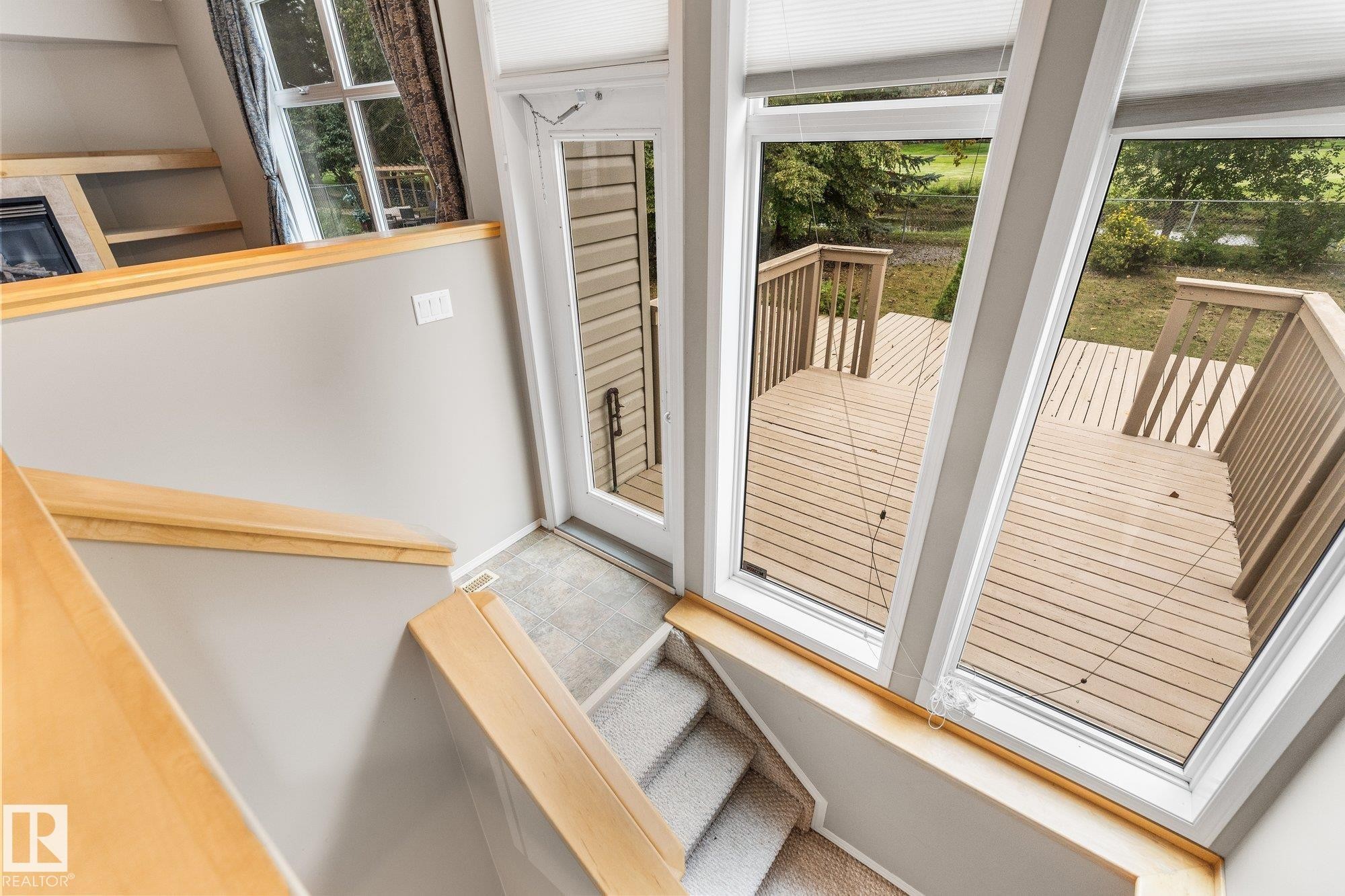 Expansive deck with wood railing, large windows with blinds, wood-finish flooring, and carpeted stairs with wood handrails - 2060 Brennan Crescent Nw, Edmonton, AB