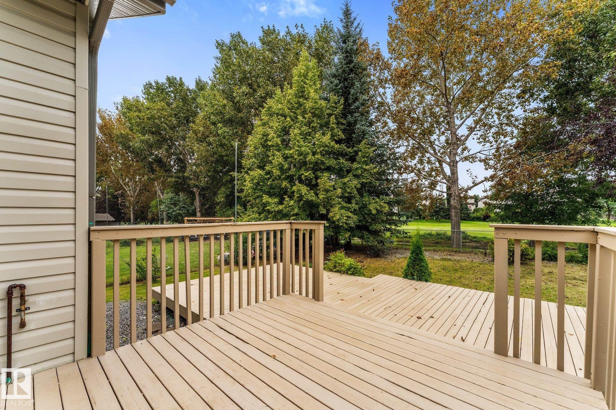 Multi-level wood deck with wood railings, leading to a landscaped yard with mature trees - 2060 Brennan Crescent Nw, Edmonton, AB