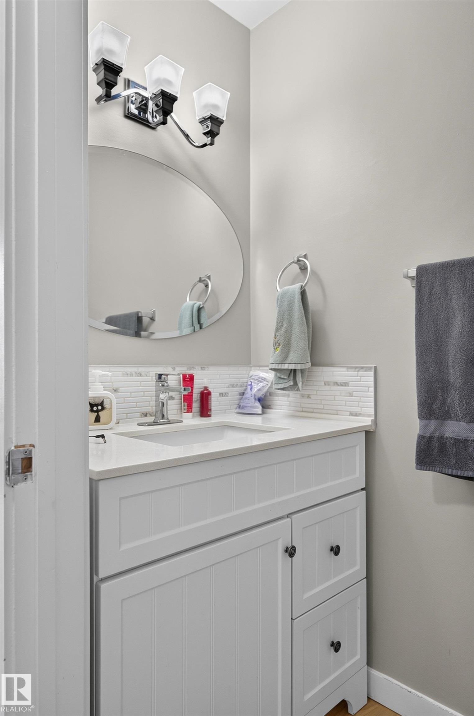 White shaker-style vanity with integrated sink, chrome faucet, white countertop, and tile backsplash - 18319 93 Avenue Nw, Edmonton, AB
