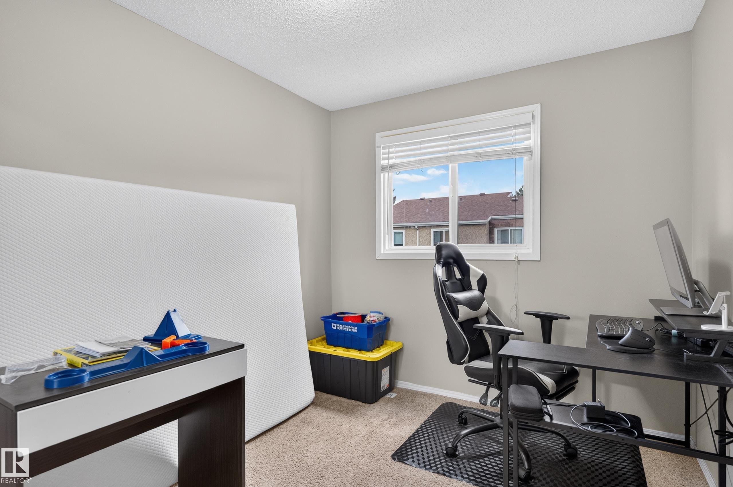 Light-filled room featuring a rectangular window with blinds, neutral wall paint, and textured carpeting - 18319 93 Avenue Nw, Edmonton, AB
