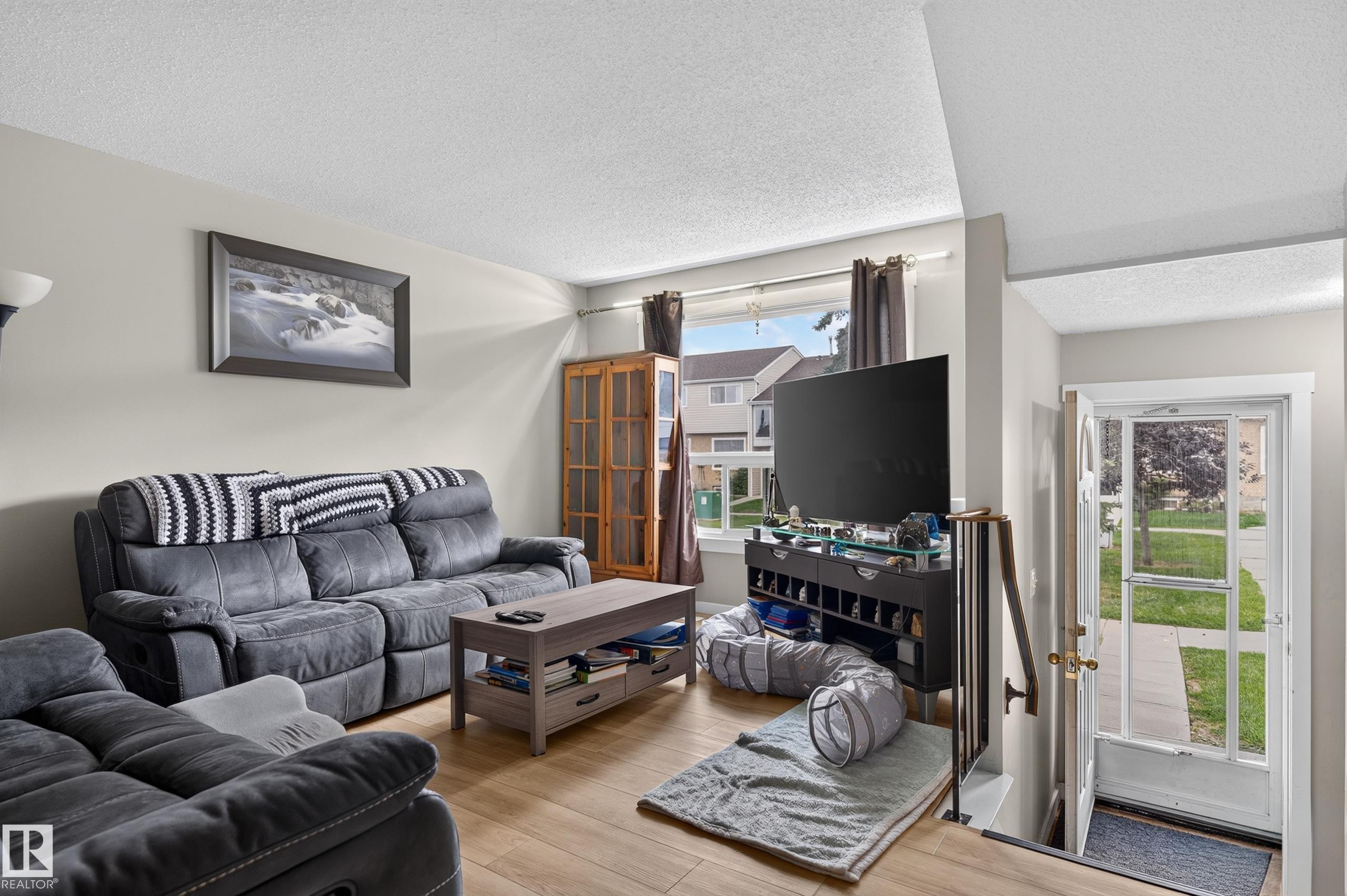 Wood-finish flooring, light-toned wall paint, large front window, and built-in shelving unit - 18319 93 Avenue Nw, Edmonton, AB