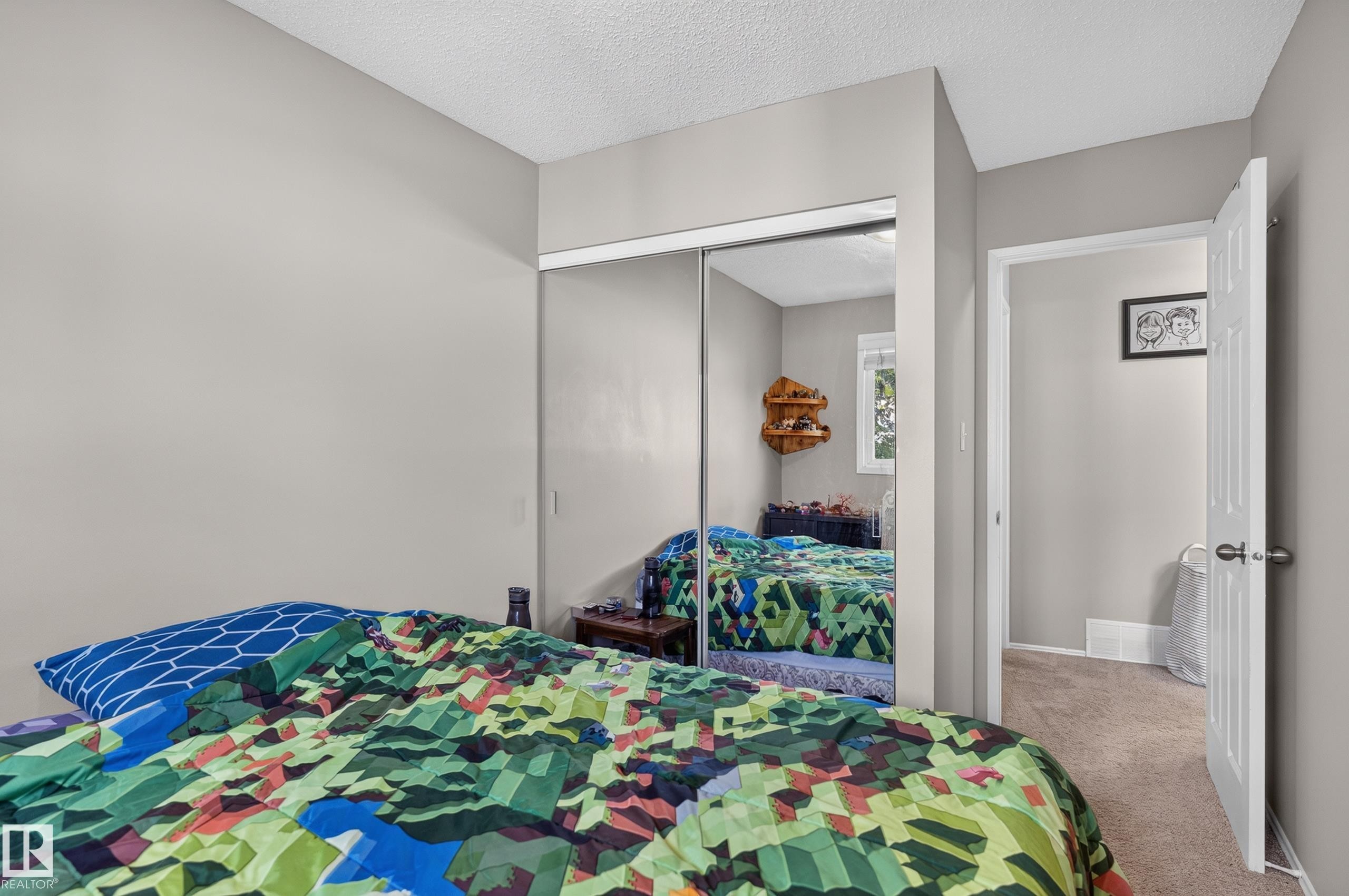 Mirrored sliding closet doors with an interior window reflection, light grey painted walls, and textured ceiling finish - 18319 93 Avenue Nw, Edmonton, AB