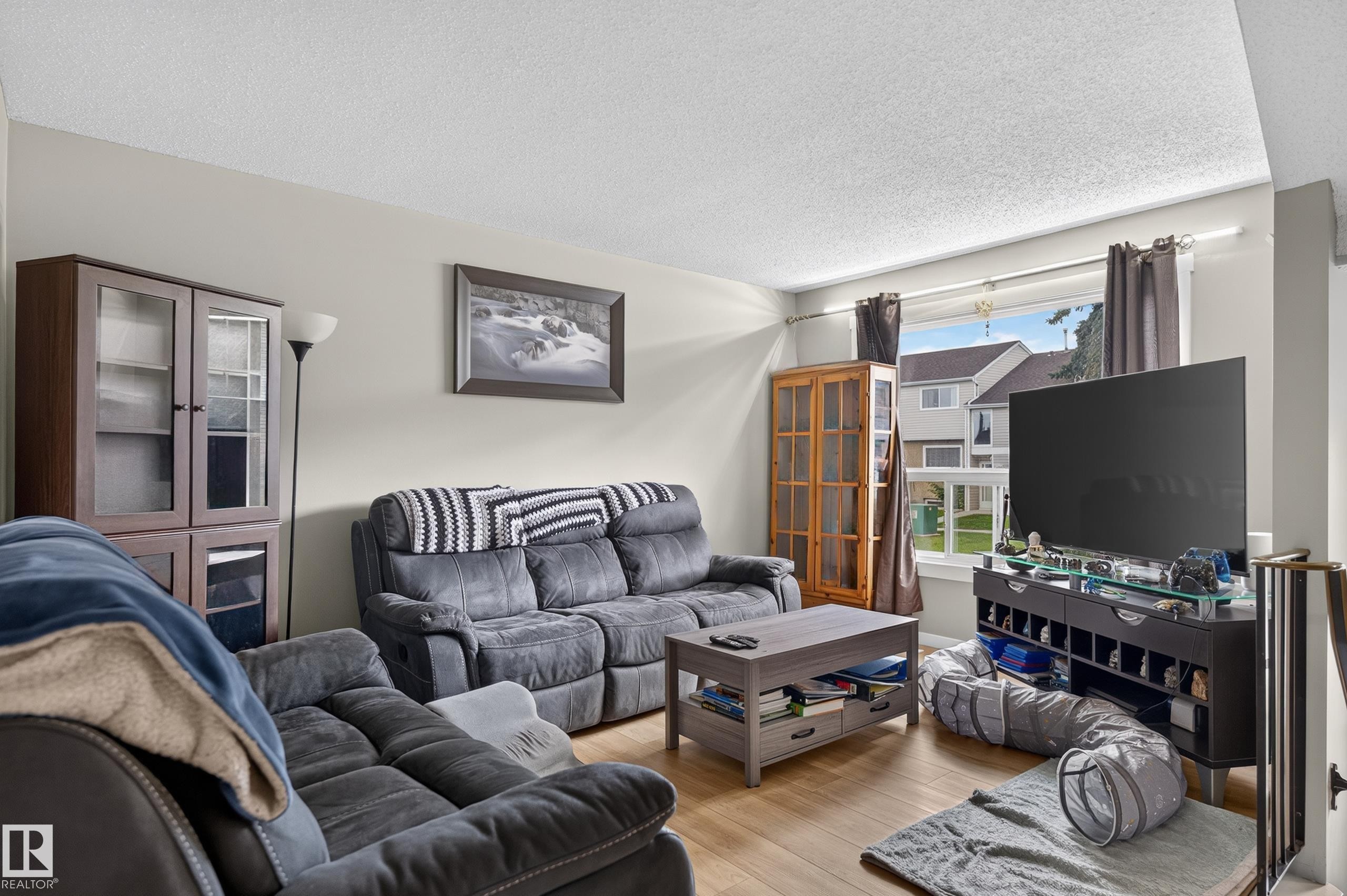 Light wood-finish flooring, neutral wall paint, and a large window providing natural illumination - 18319 93 Avenue Nw, Edmonton, AB