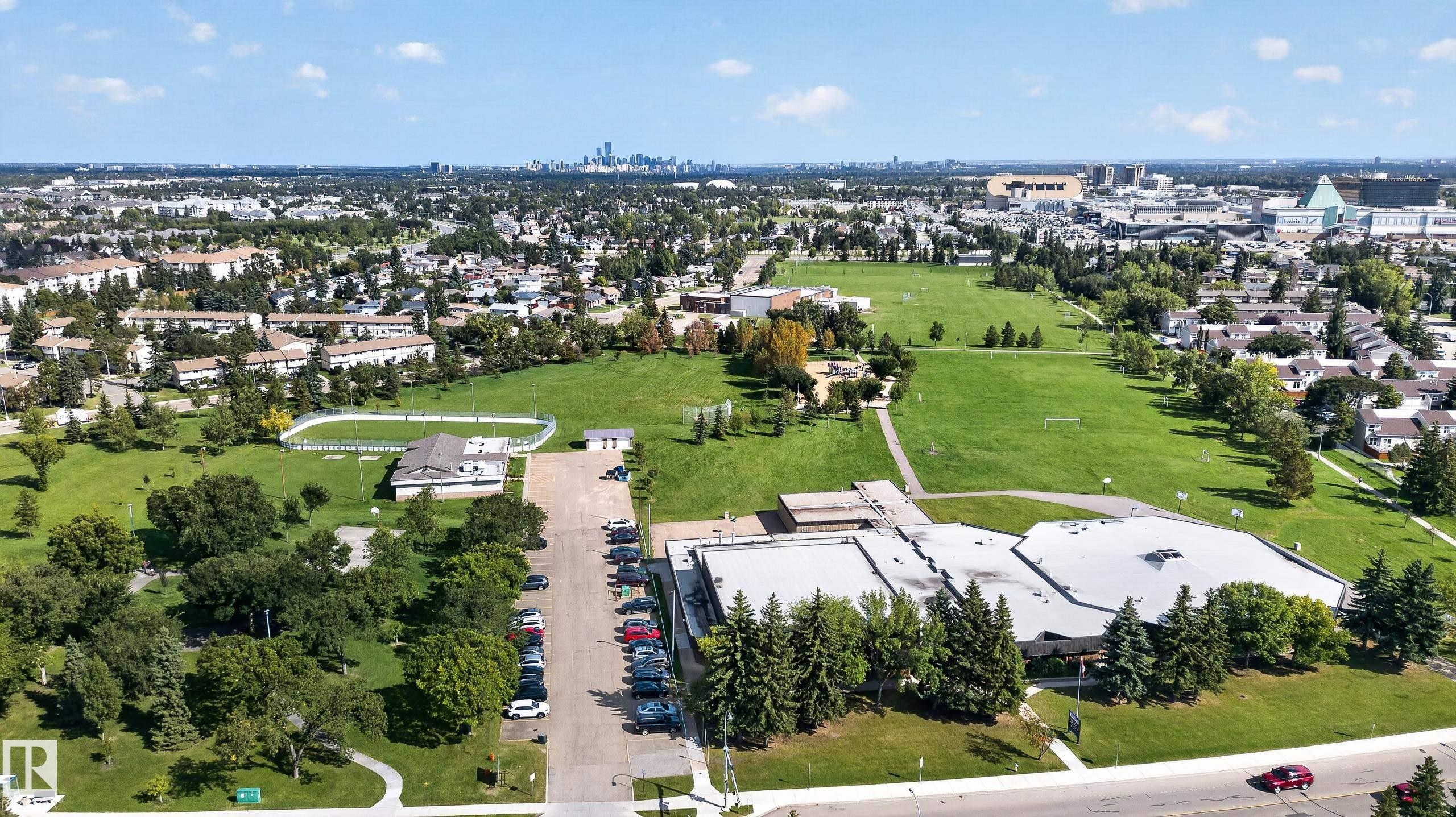 Expansive grounds featuring a building with a large parking area, surrounding green spaces, and mature trees - 18319 93 Avenue Nw, Edmonton, AB
