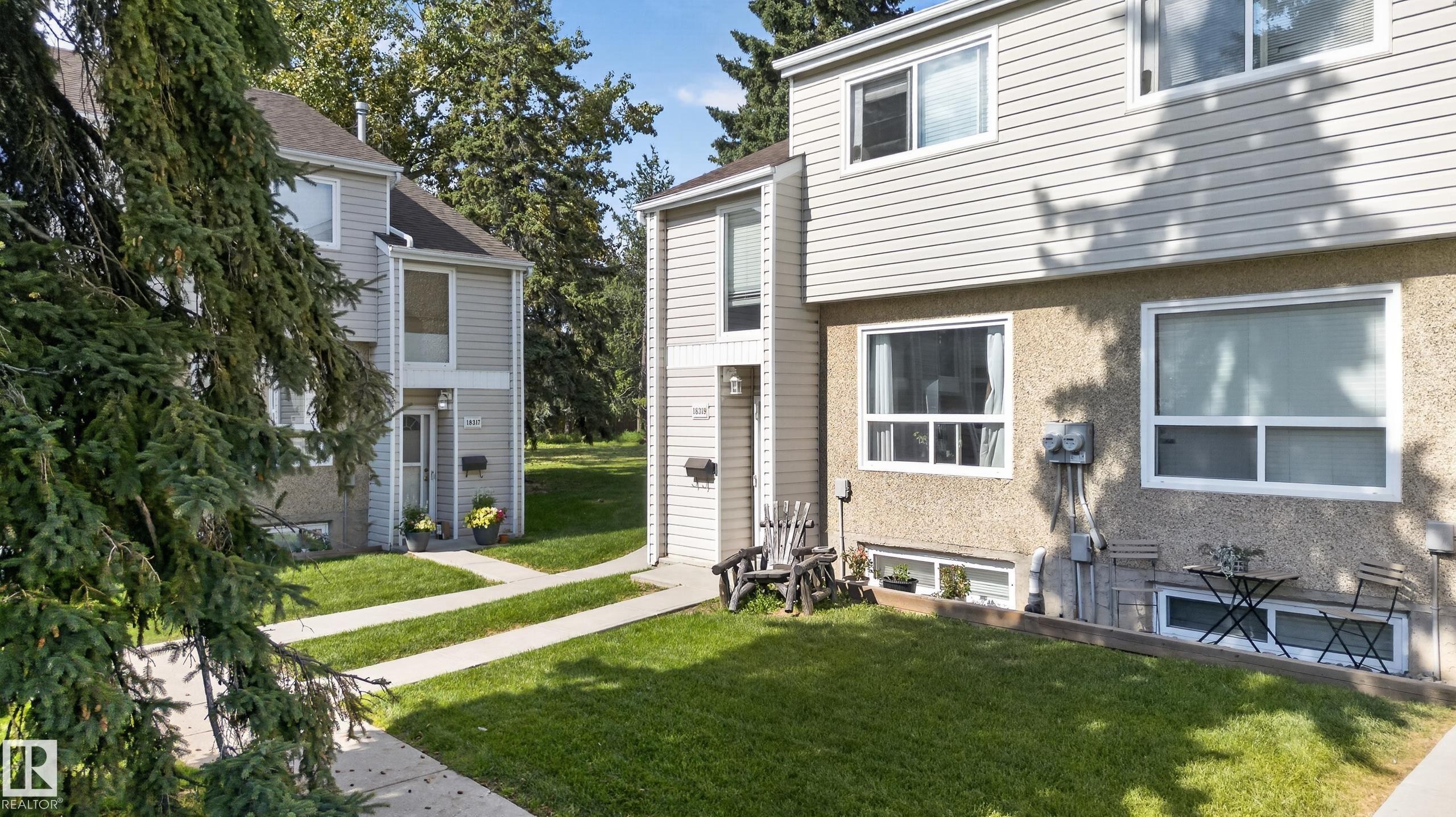 Two-story exterior with light-colored siding and stucco finishes, featuring multiple windows and a front entry - 18319 93 Avenue Nw, Edmonton, AB
