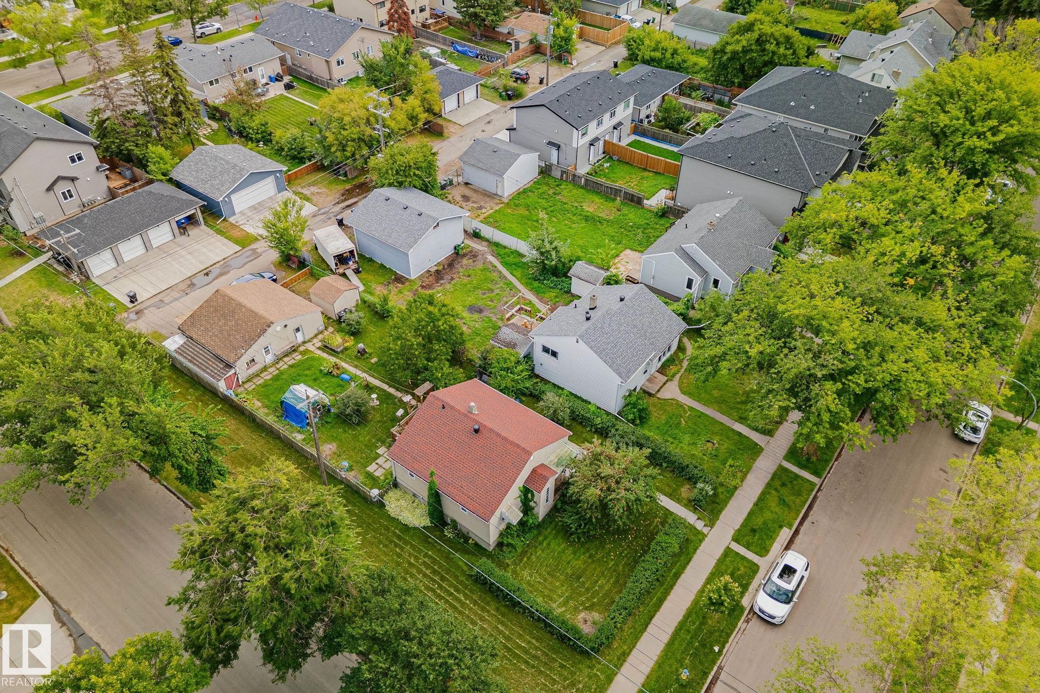 Aerial perspective showcasing a residential neighborhood with mature trees, green lawns, and diverse housing styles - 11935 125 Street Nw, Edmonton, AB