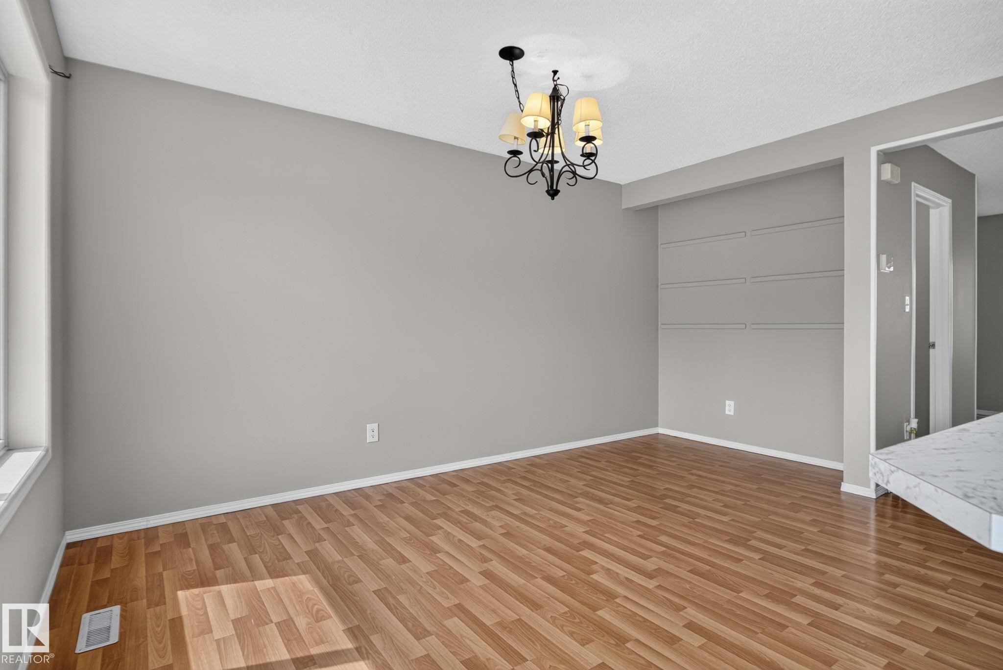 Wood-finish flooring, recessed wall shelving, and a decorative chandelier - 8923 173 Avenue Nw, Edmonton, AB