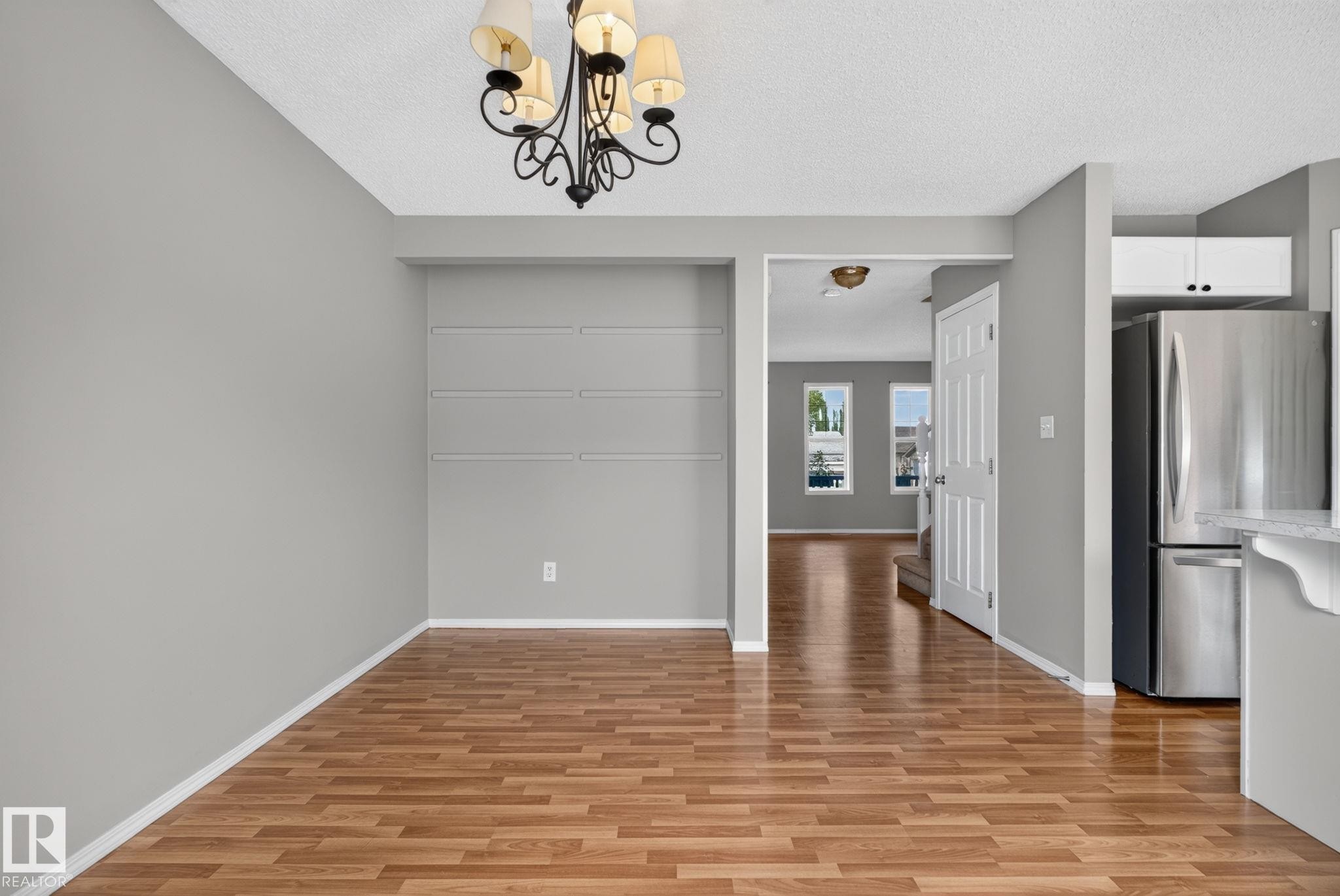 Wood-finish flooring throughout, light gray wall finishes, and a decorative chandelier - 8923 173 Avenue Nw, Edmonton, AB