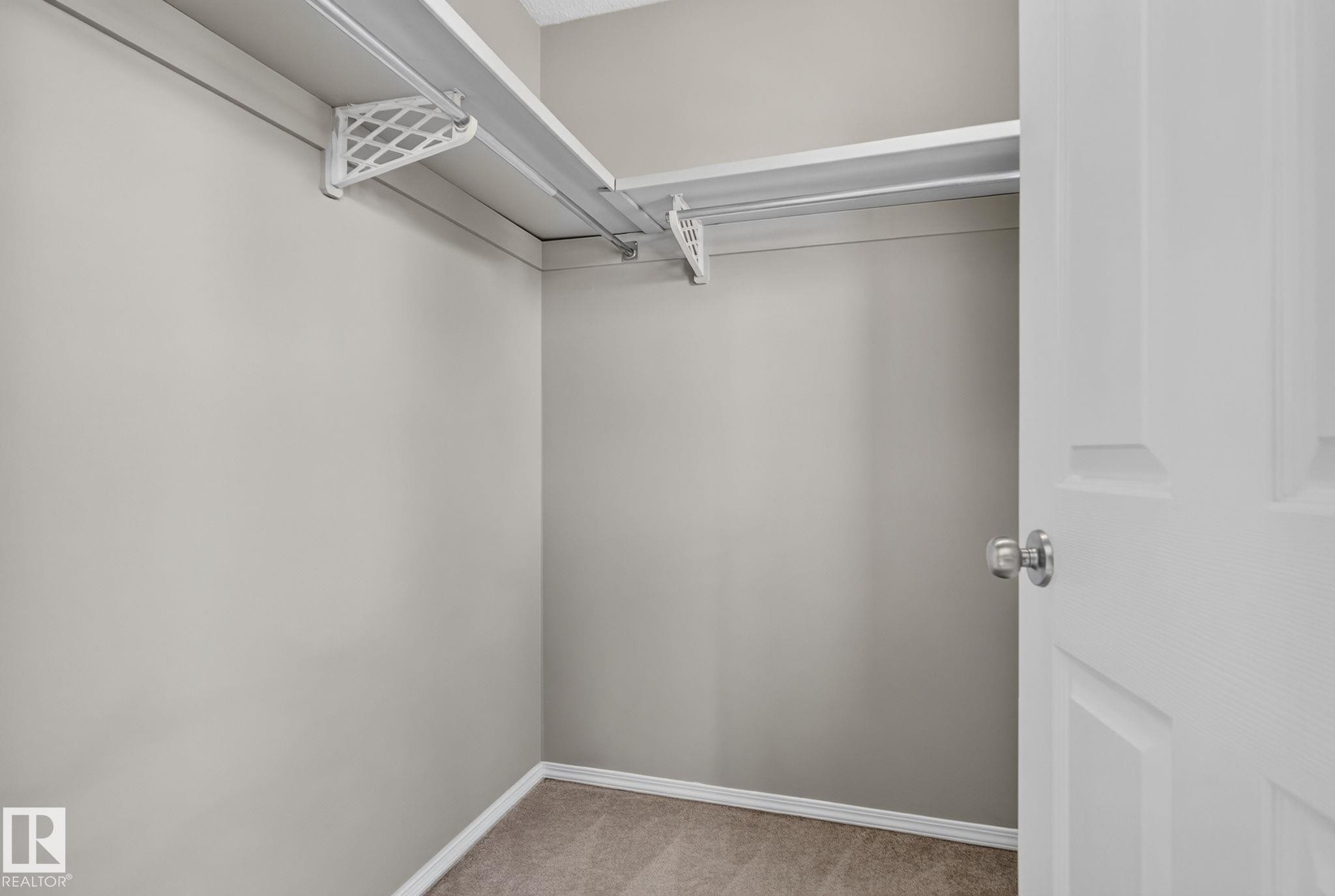 Carpeted interior closet with neutral wall paint, white trim, and metal shelving system - 8923 173 Avenue Nw, Edmonton, AB