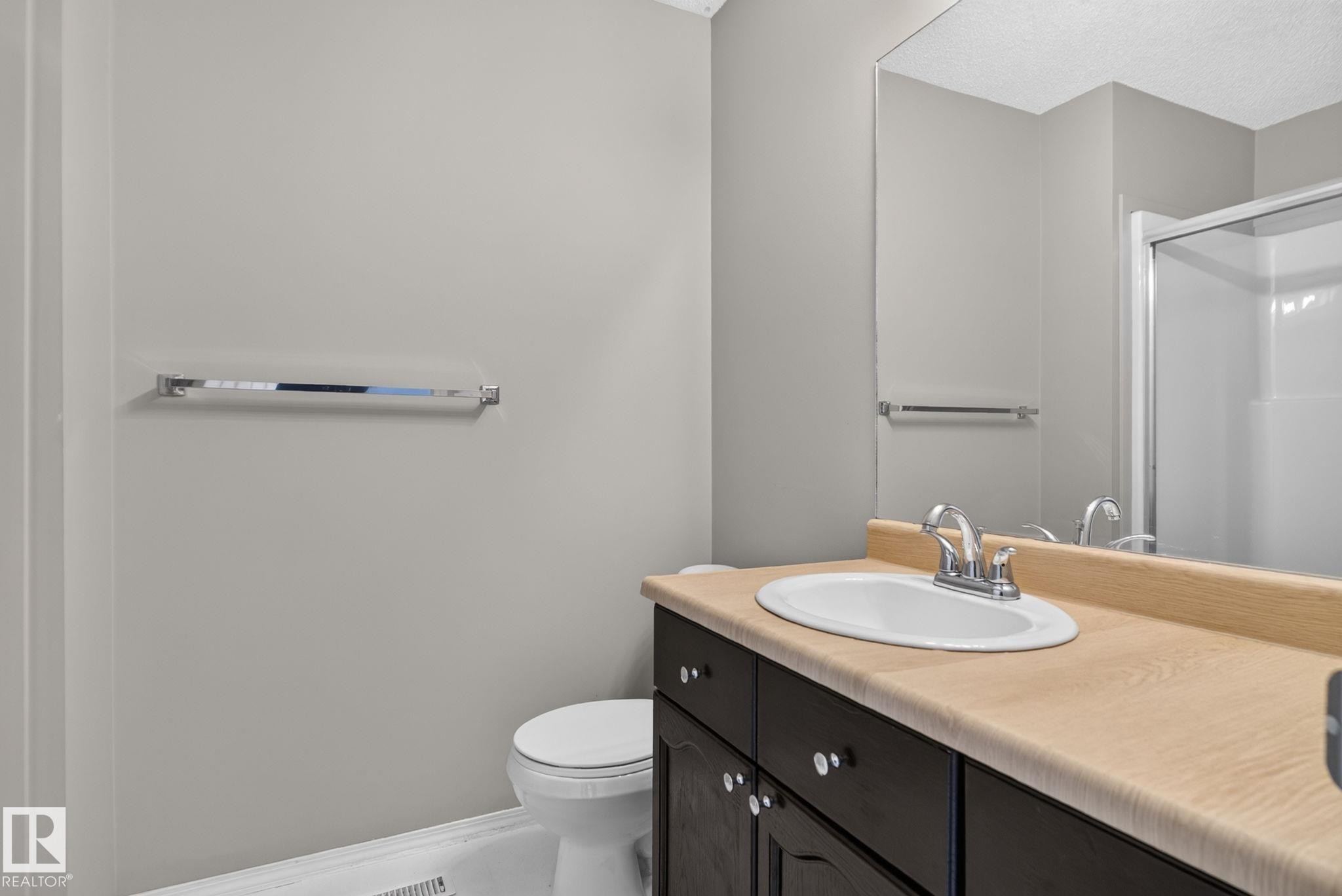 Dark wood-finish vanity with a light countertop, an integrated sink, and a chrome faucet - 8923 173 Avenue Nw, Edmonton, AB
