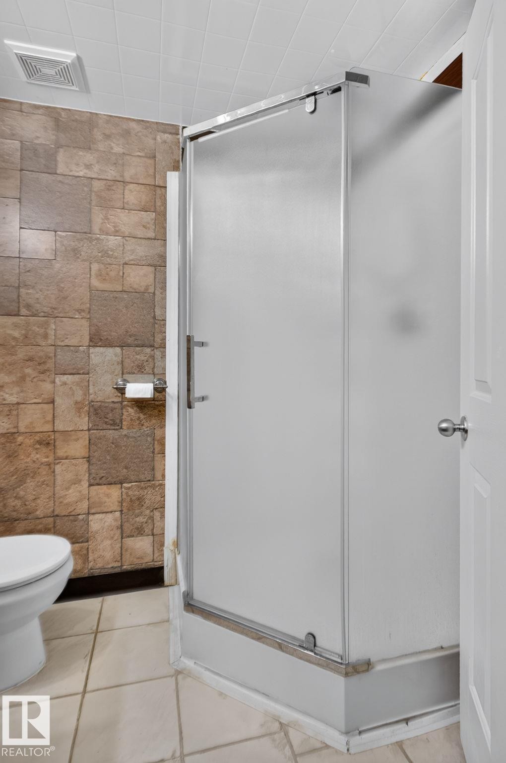 Shower enclosure with frosted glass panels, tile flooring, and textured wall tiles - 8923 173 Avenue Nw, Edmonton, AB
