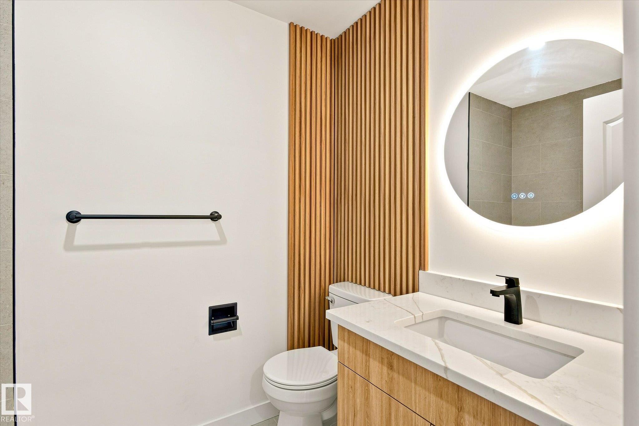 Modern vanity with wood-finish cabinetry, integrated rectangular sink, and light-toned countertop - 17325 85 Avenue Nw, Edmonton, AB