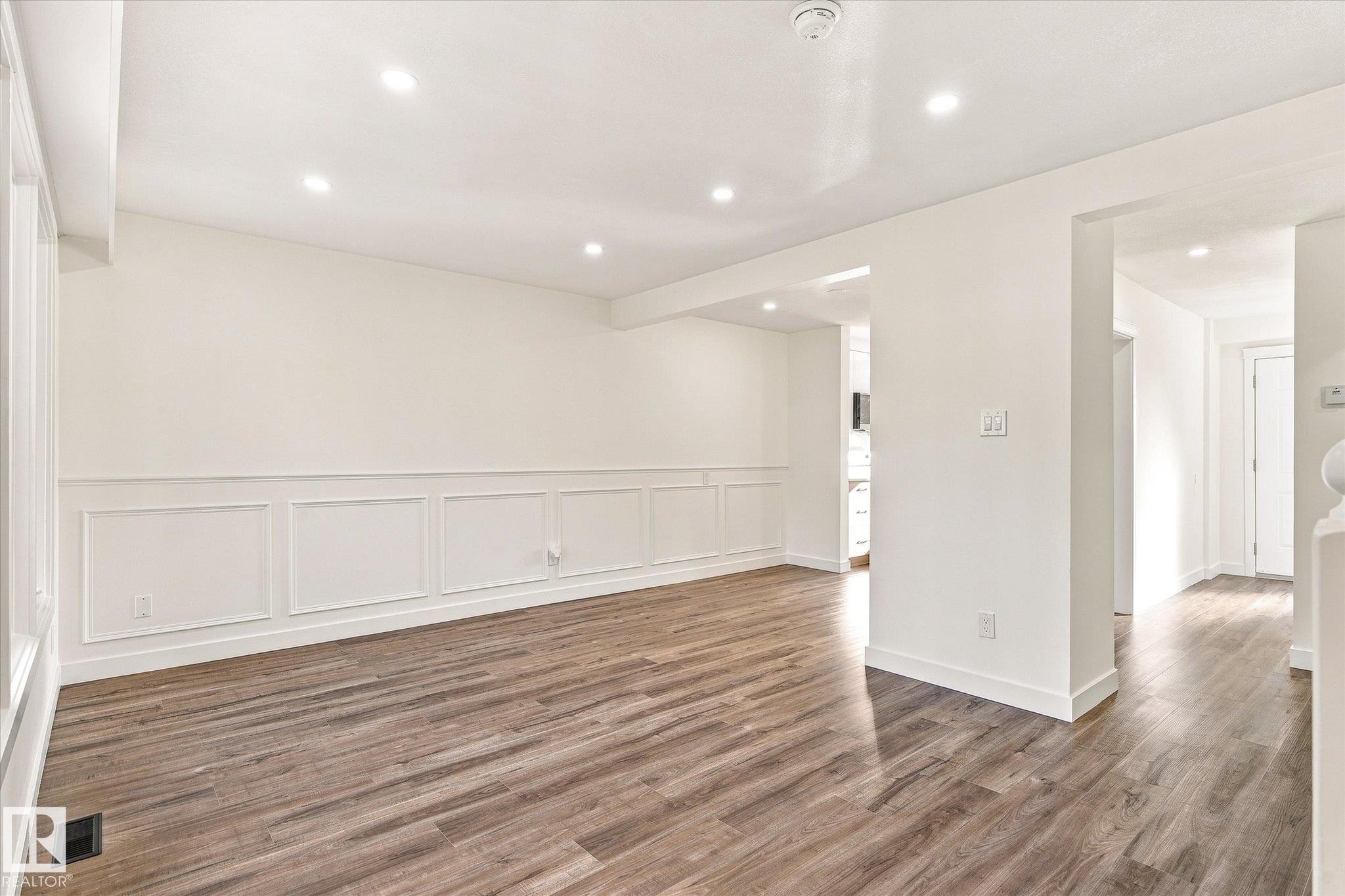 Recessed lighting illuminating the room, wood-finish flooring, and white paneled wainscoting - 17325 85 Avenue Nw, Edmonton, AB
