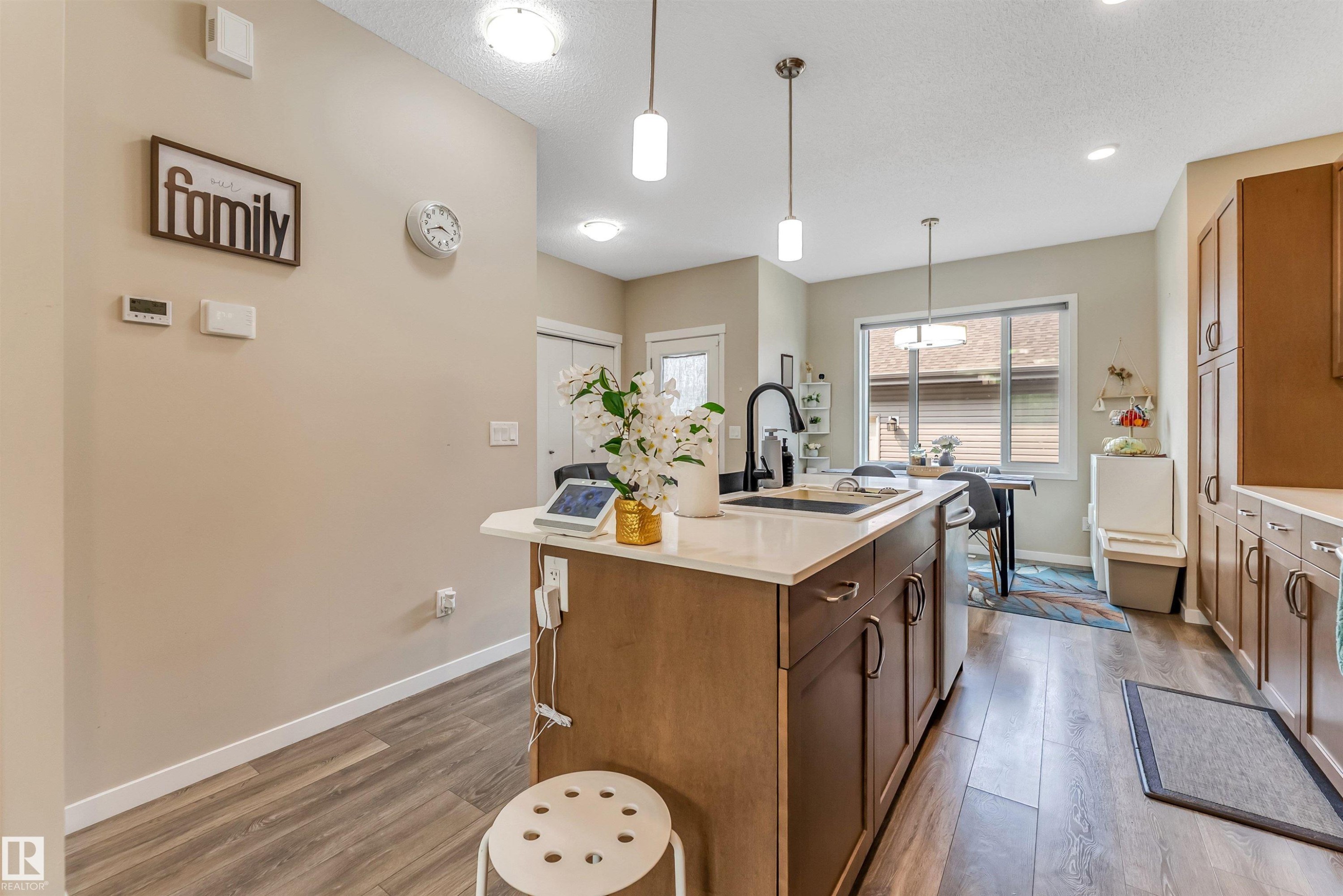 Contemporary kitchen island featuring a white countertop, undermount sink with a gooseneck faucet, and wood-finish cabinetry - 1514 26 Avenue Nw, Edmonton, AB - Indoor Photo Showing Kitchen With Upgraded Kitchen