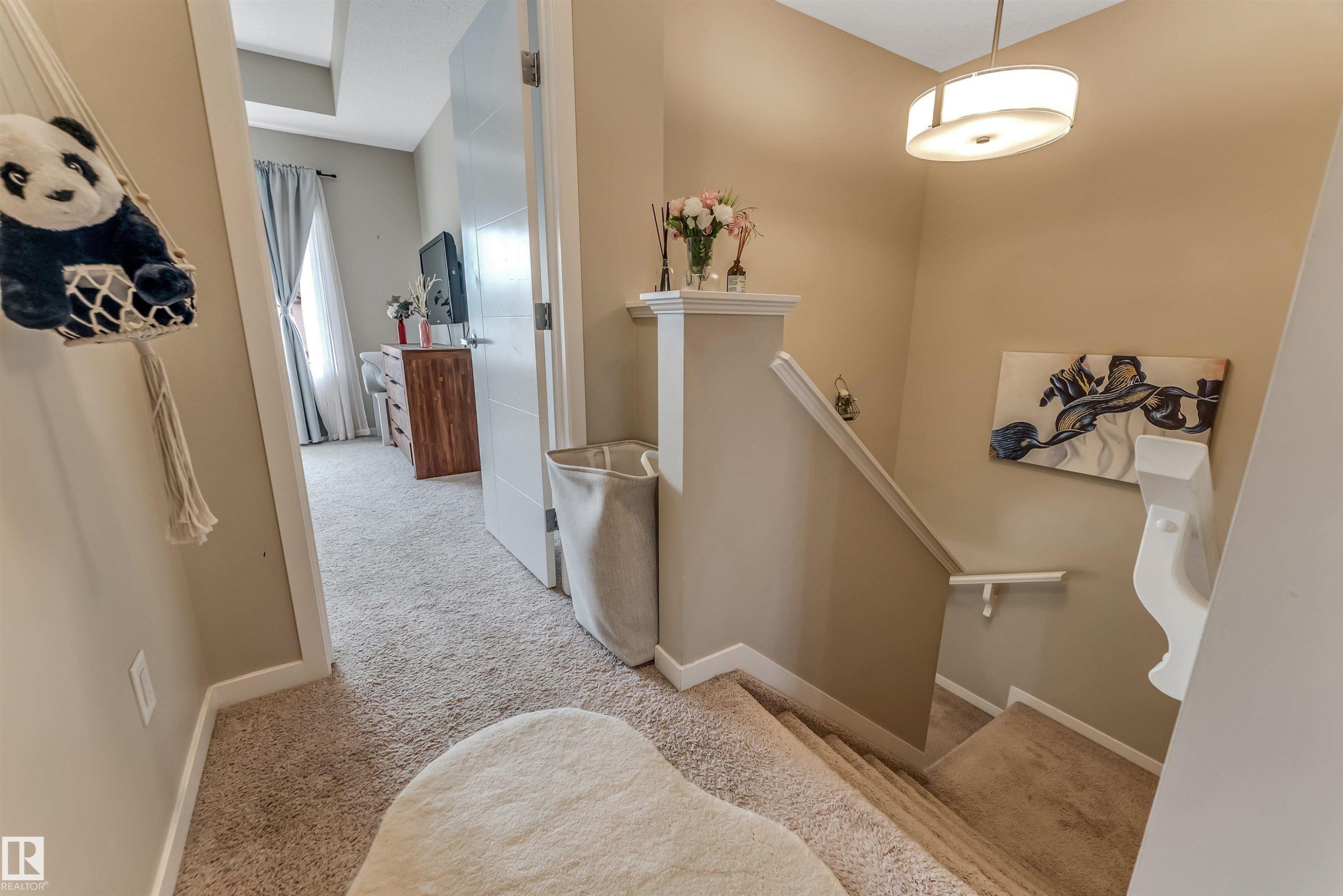 Carpeted hallway and staircase featuring light tan wall paint, white trim, a modern semi-flush mount light fixture, and a white interior door - 1514 26 Avenue Nw, Edmonton, AB - Indoor Photo Showing Other Room