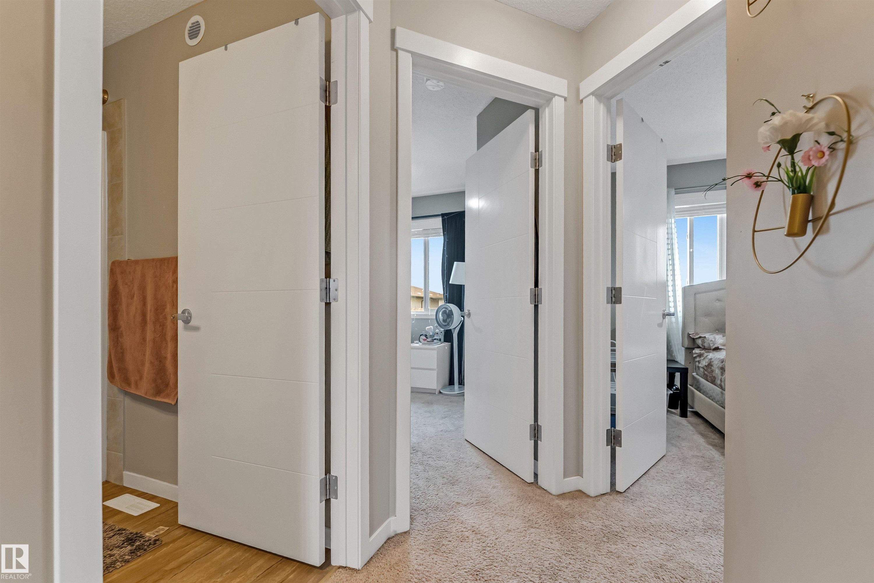 Interior hallway featuring white paneled doors with horizontal detailing, light beige walls, and light-colored carpeting - 1514 26 Avenue Nw, Edmonton, AB - Indoor Photo Showing Other Room