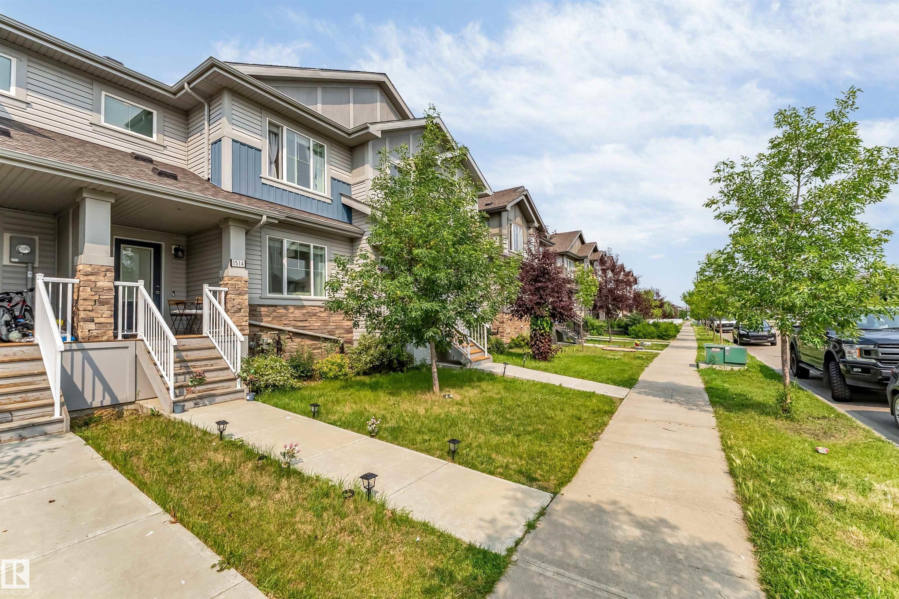 Modern townhome exterior featuring multi-toned siding, stone accents, and a covered porch entry - 1514 26 Avenue Nw, Edmonton, AB - Outdoor With Facade