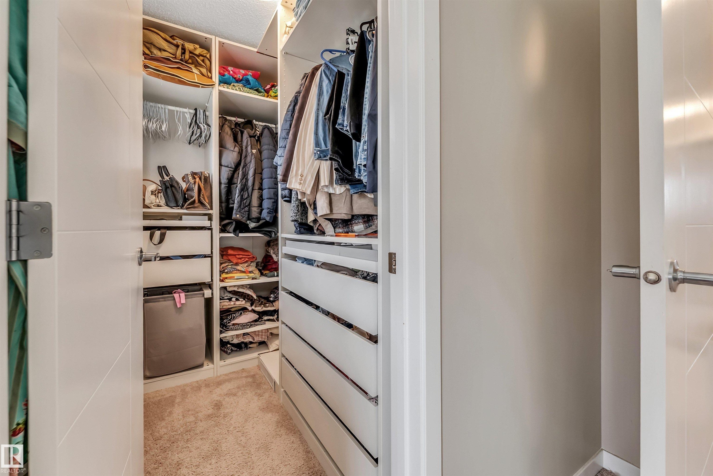 Custom closet system featuring integrated shelving, hanging rods, and pull-out drawers - 1514 26 Avenue Nw, Edmonton, AB - Indoor With Storage
