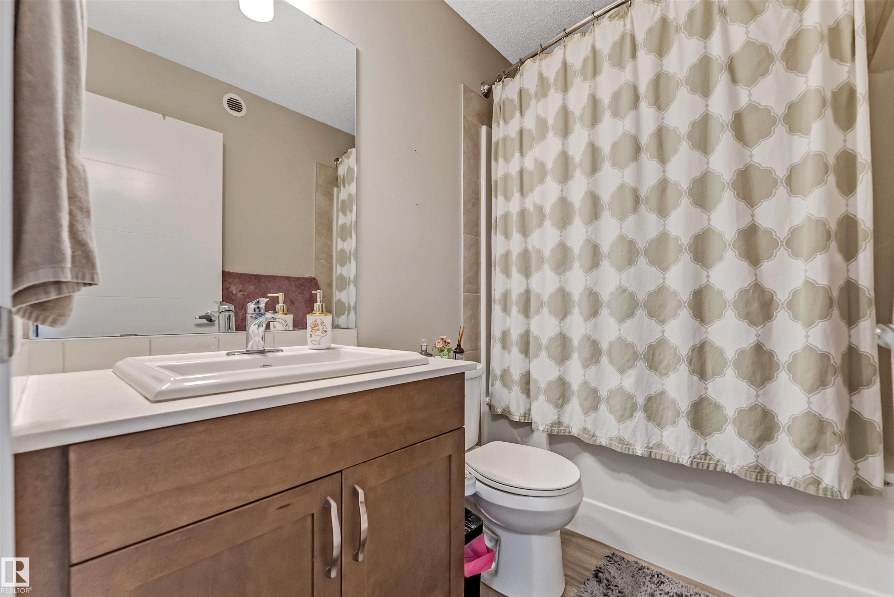 Bathroom vanity featuring a rectangular sink, chrome faucet, and wood-finish cabinetry - 1514 26 Avenue Nw, Edmonton, AB - Indoor Photo Showing Bathroom