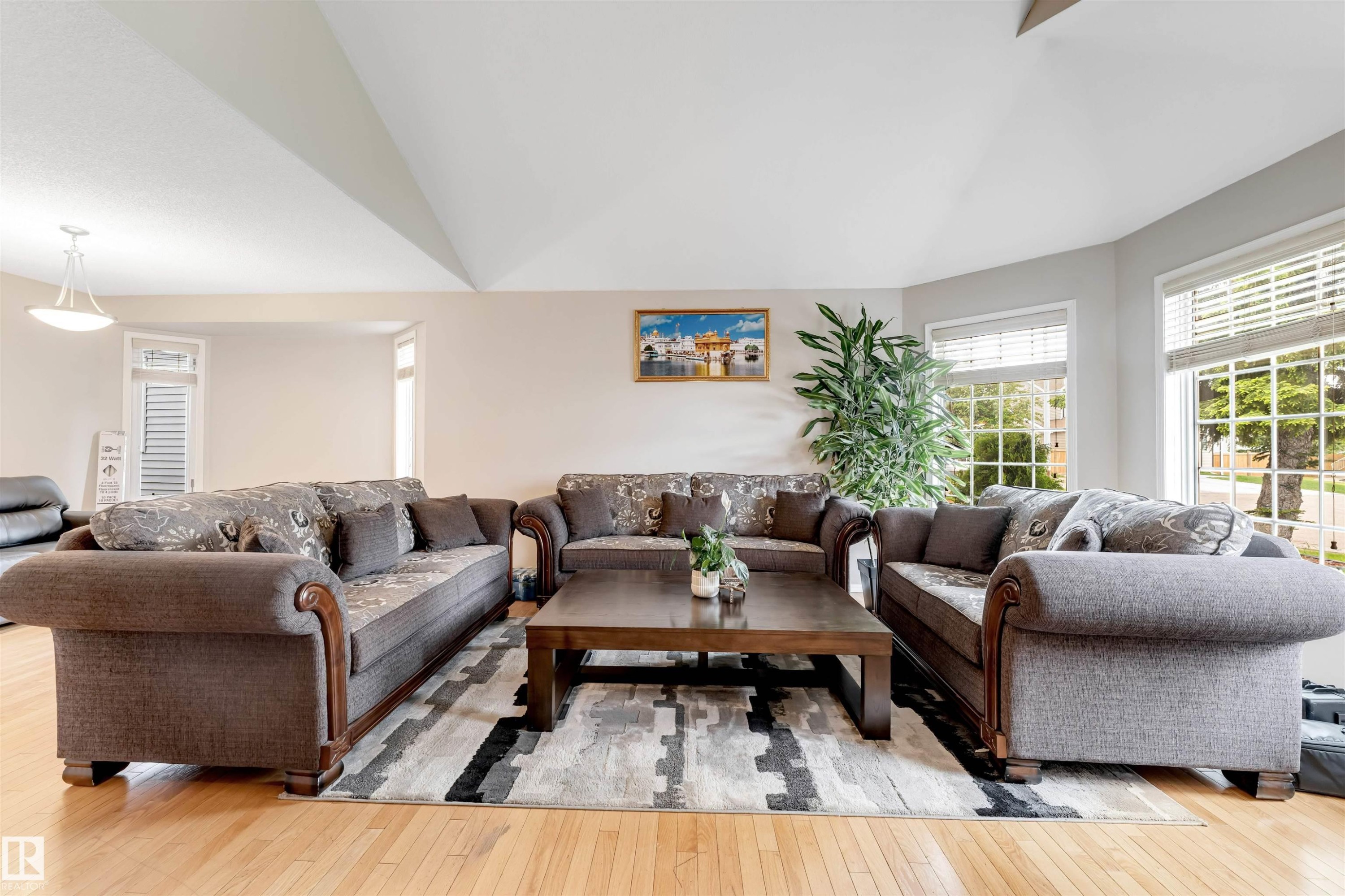 Living area featuring hardwood flooring, multiple windows providing ample natural light, a vaulted ceiling, and recessed lighting - 4465 32A Street Nw, Edmonton, AB - Indoor Photo Showing Living Room