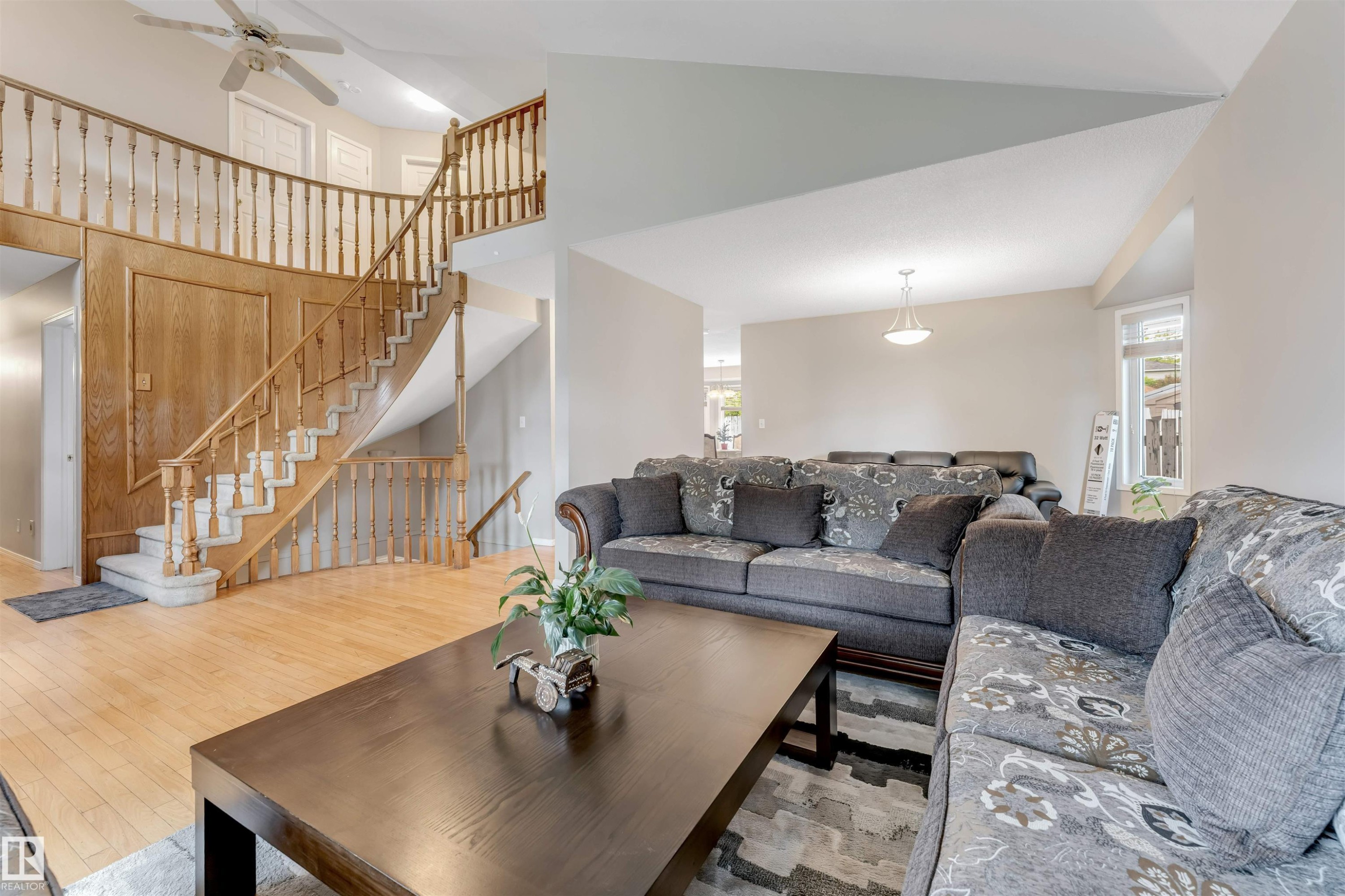 Two-story foyer featuring light wood-finish flooring and a curved staircase with wood balusters - 4465 32A Street Nw, Edmonton, AB - Indoor Photo Showing Living Room