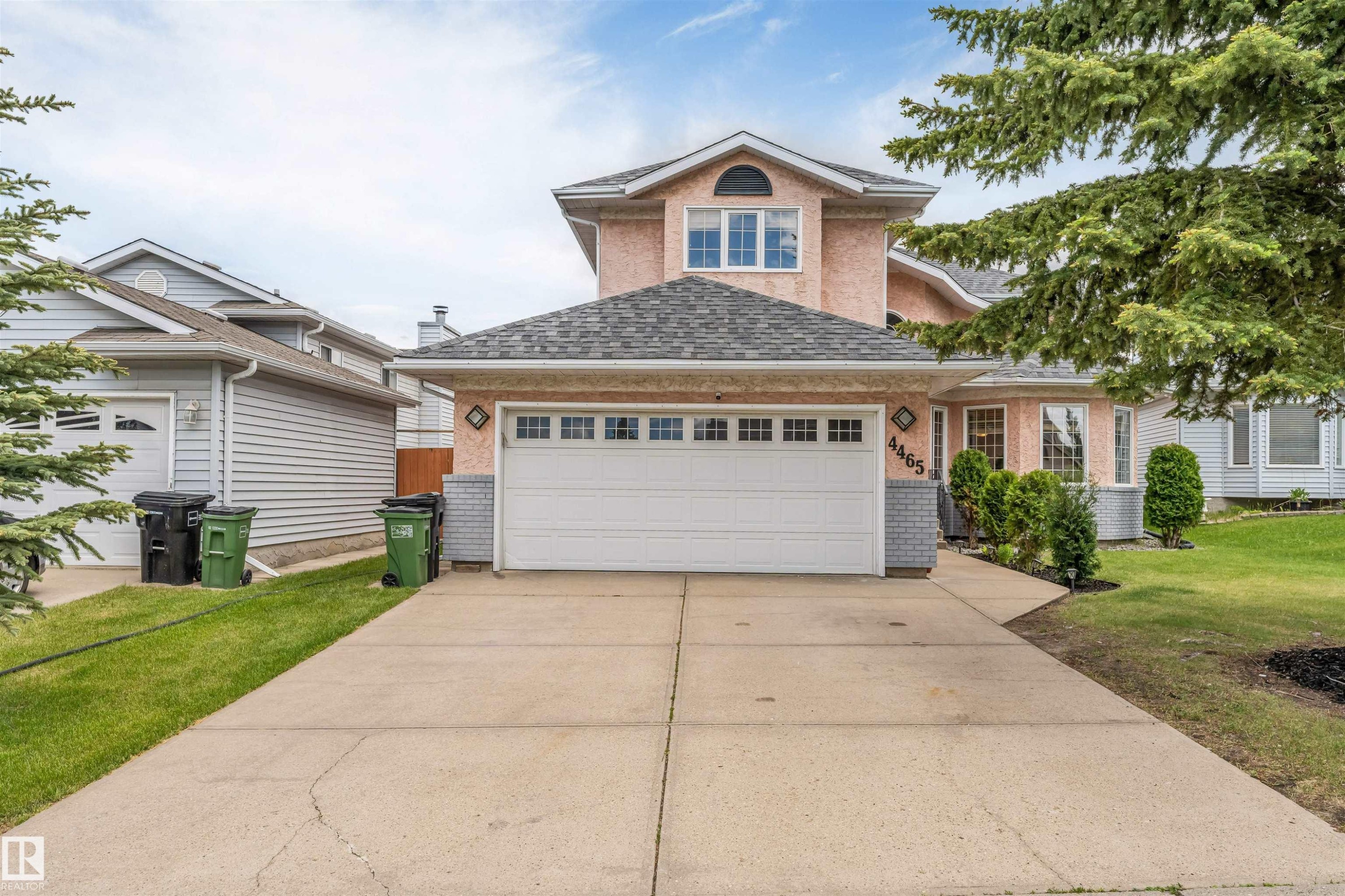 Two-story stucco exterior featuring a prominent front-facing garage with a windowed overhead door - 4465 32A Street Nw, Edmonton, AB - Outdoor With Facade