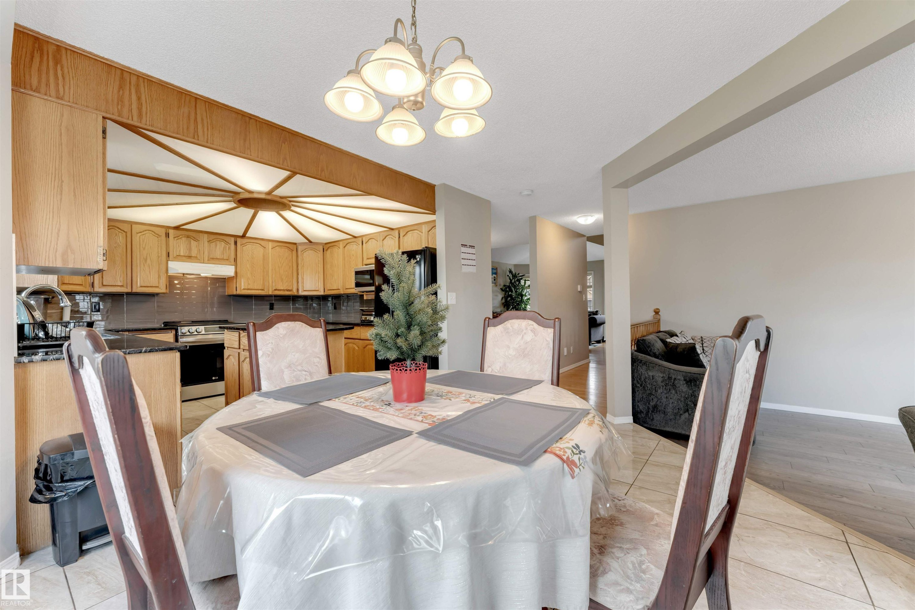 Eat-in kitchen featuring light wood cabinetry, dark countertops, and a tiled backsplash - 4465 32A Street Nw, Edmonton, AB - Indoor Photo Showing Dining Room
