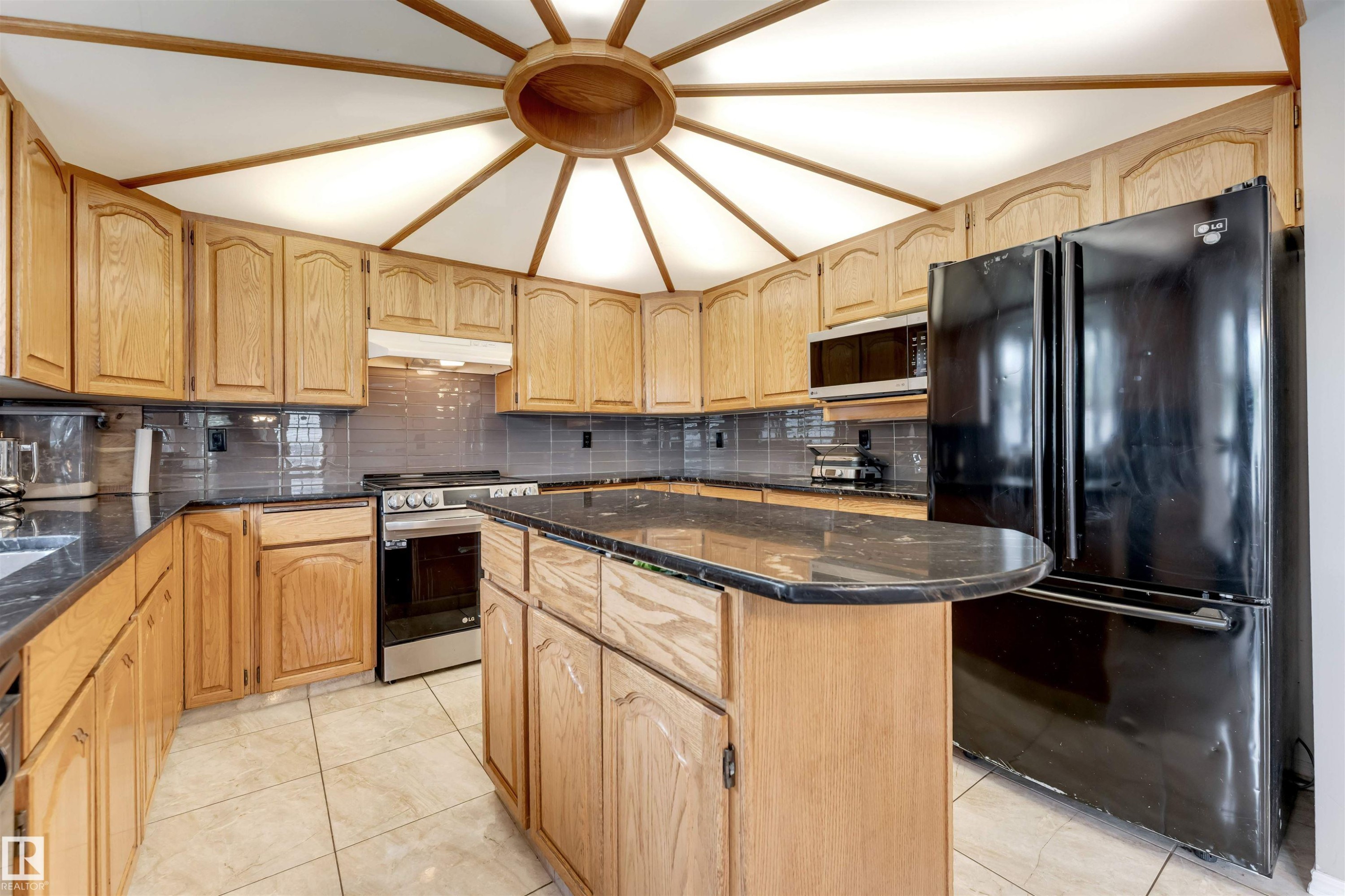 Kitchen featuring a radial wood-paneled ceiling with central lighting, wood cabinetry, dark countertops, a tiled backsplash, and light tile flooring - 4465 32A Street Nw, Edmonton, AB - Indoor Photo Showing Kitchen