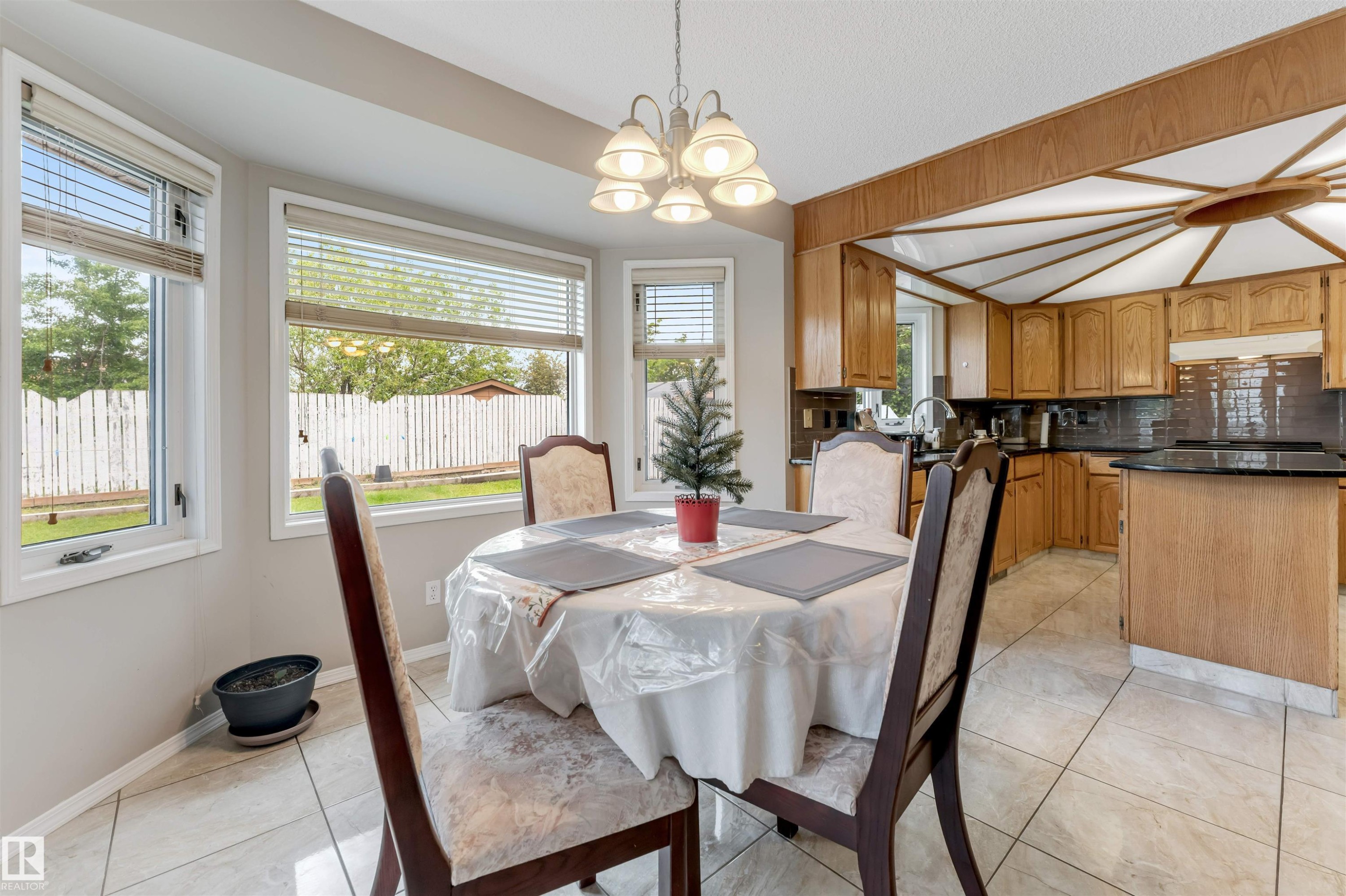 Dining area featuring large bay windows, a multi-light chandelier, and light-toned tile flooring - 4465 32A Street Nw, Edmonton, AB - Indoor Photo Showing Dining Room