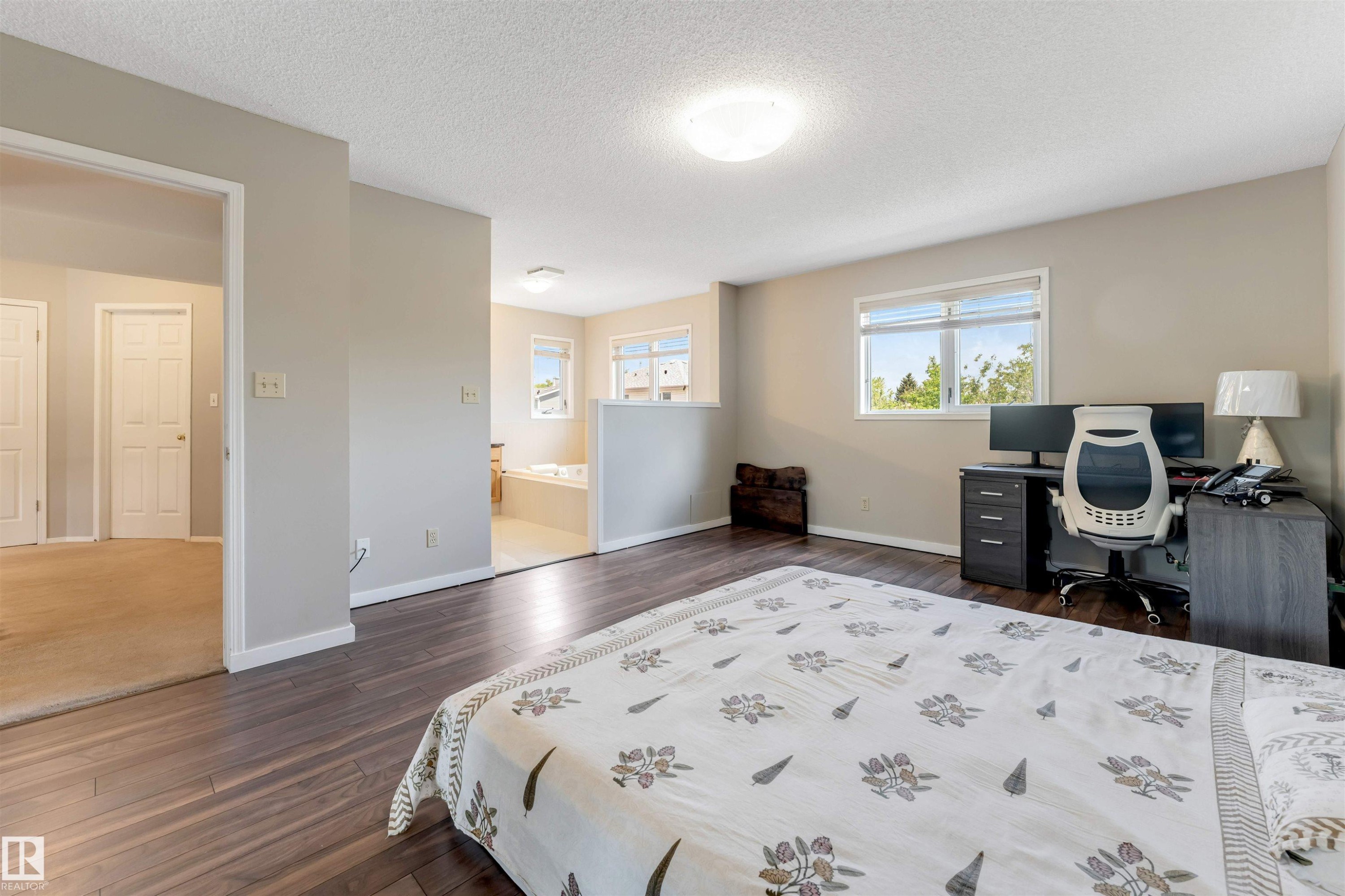 Spacious room featuring wood-finish flooring, light neutral wall tones, and multiple windows - 4465 32A Street Nw, Edmonton, AB - Indoor Photo Showing Bedroom