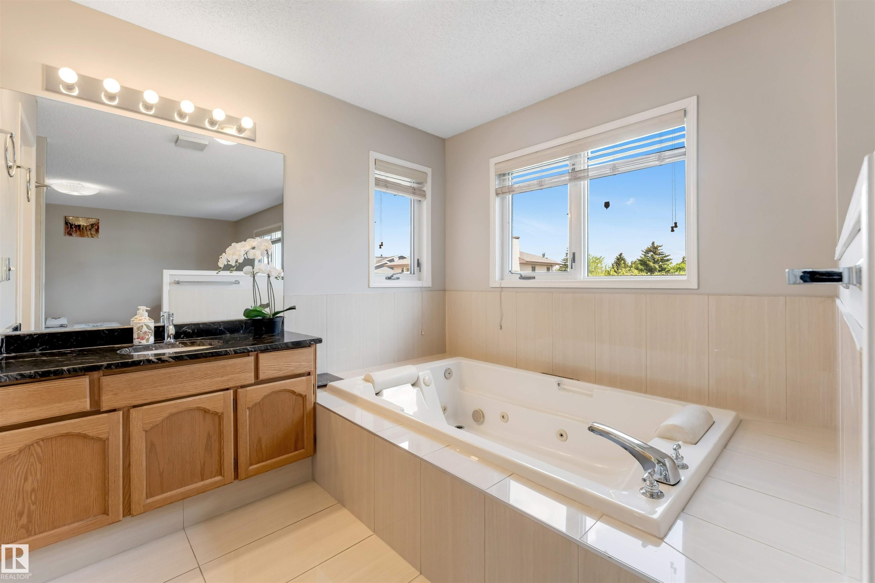 Jetted tub with chrome fixtures, set against a tiled surround and light-colored walls - 4465 32A Street Nw, Edmonton, AB - Indoor Photo Showing Bathroom