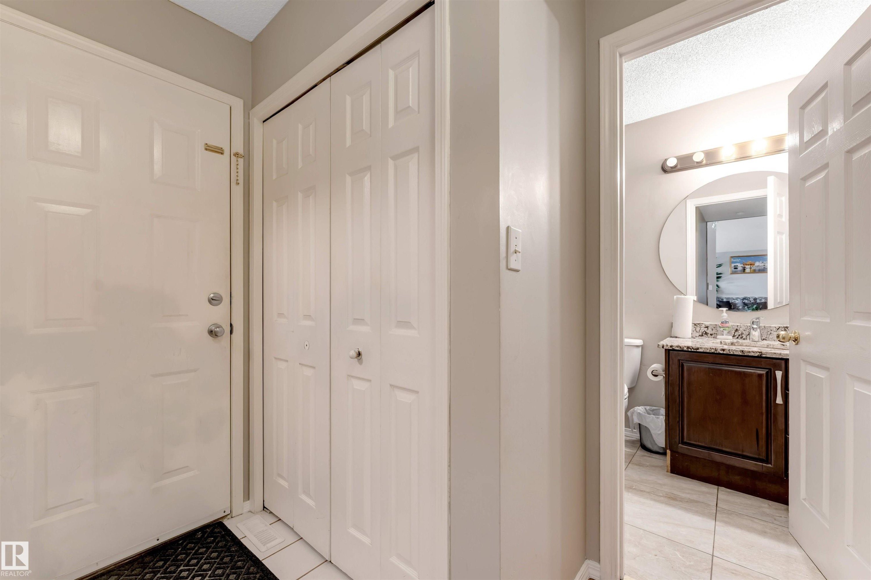 Entryway featuring a white paneled door, bi-fold closet doors, and light tile flooring - 4465 32A Street Nw, Edmonton, AB - Indoor Photo Showing Other Room