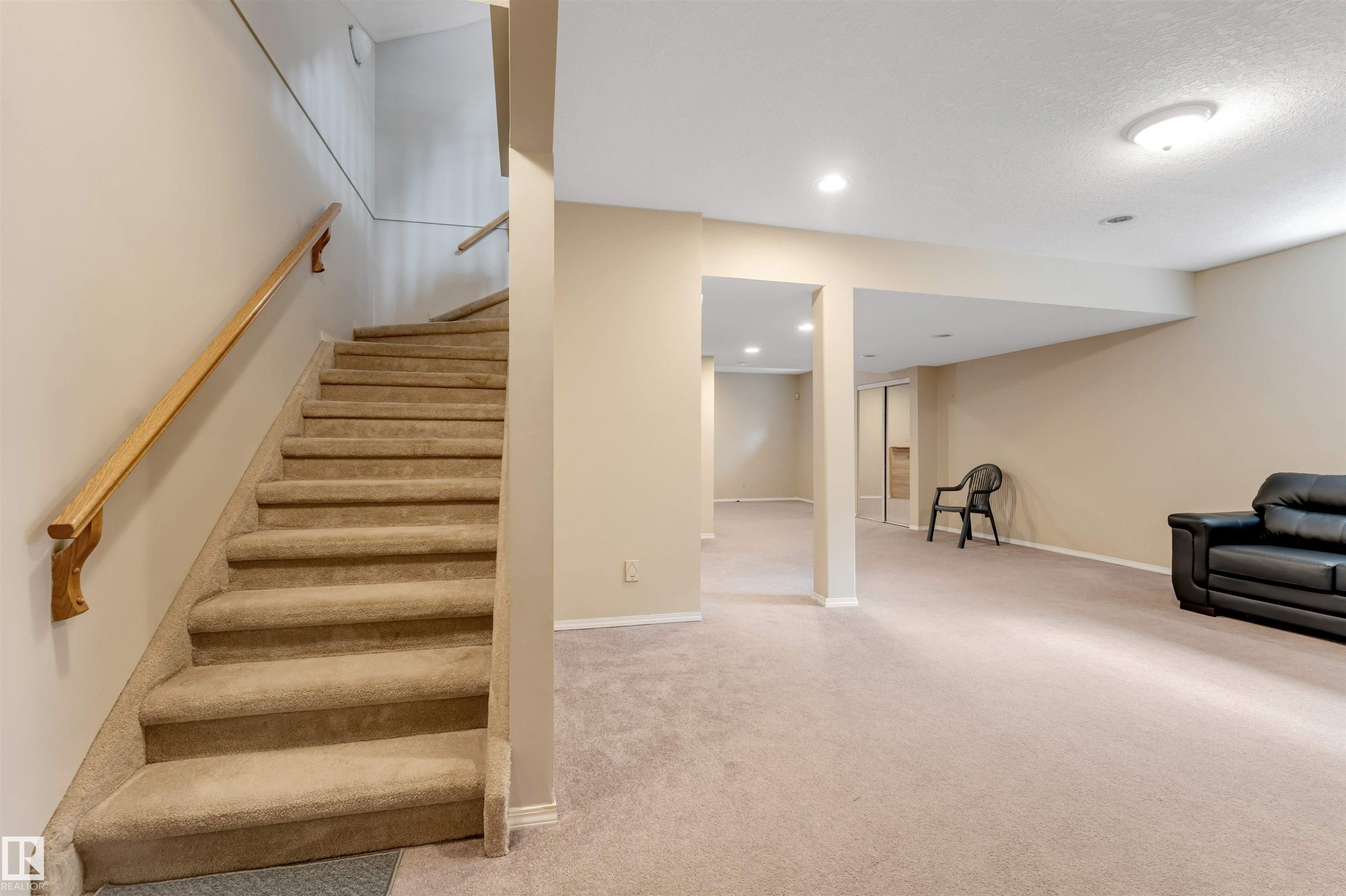 Carpeted staircase with wood handrail - 4465 32A Street Nw, Edmonton, AB - Indoor Photo Showing Other Room