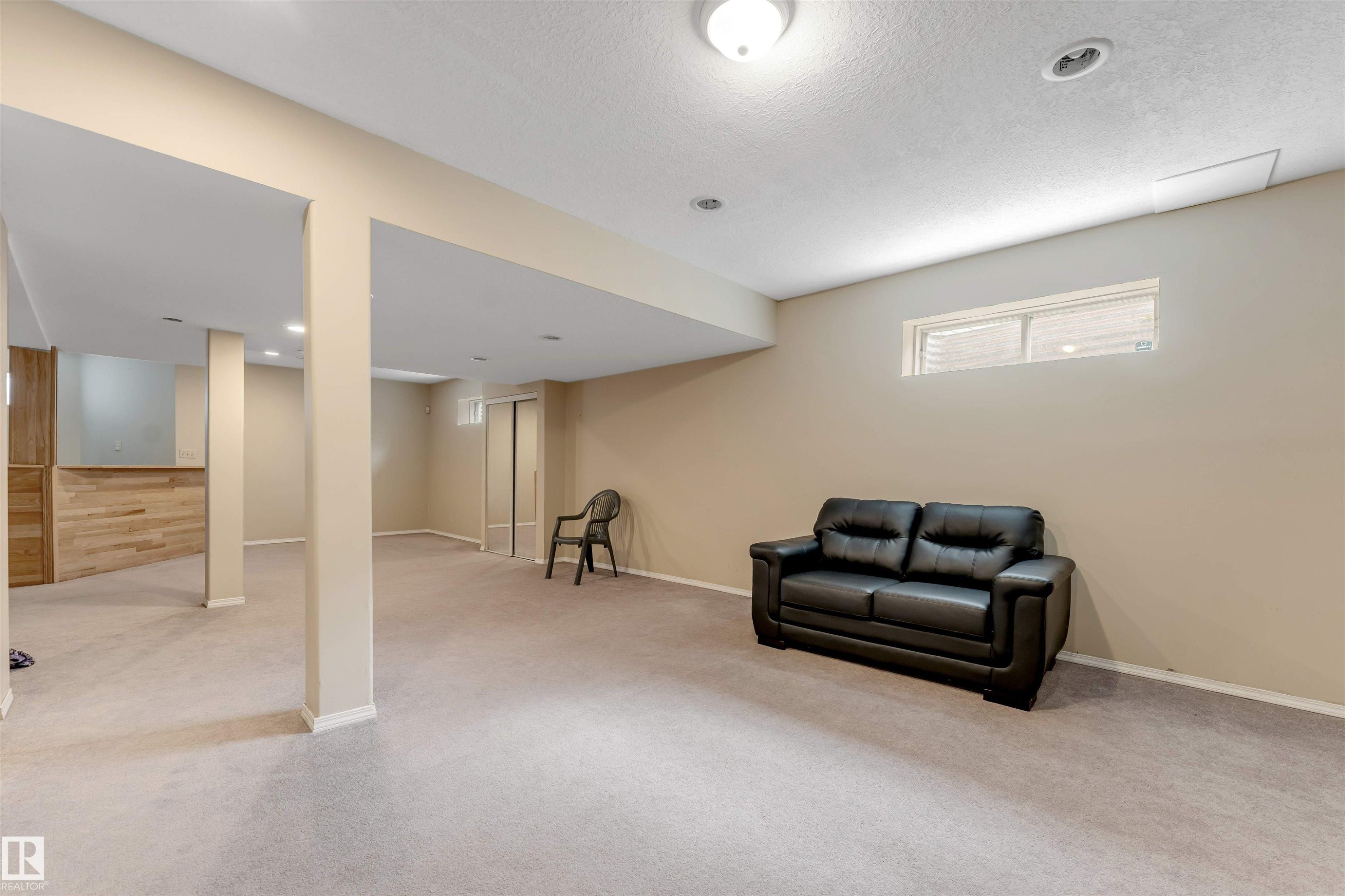 Spacious lower-level room featuring light tan walls, recessed lighting, and a light gray carpet - 4465 32A Street Nw, Edmonton, AB - Indoor Photo Showing Other Room