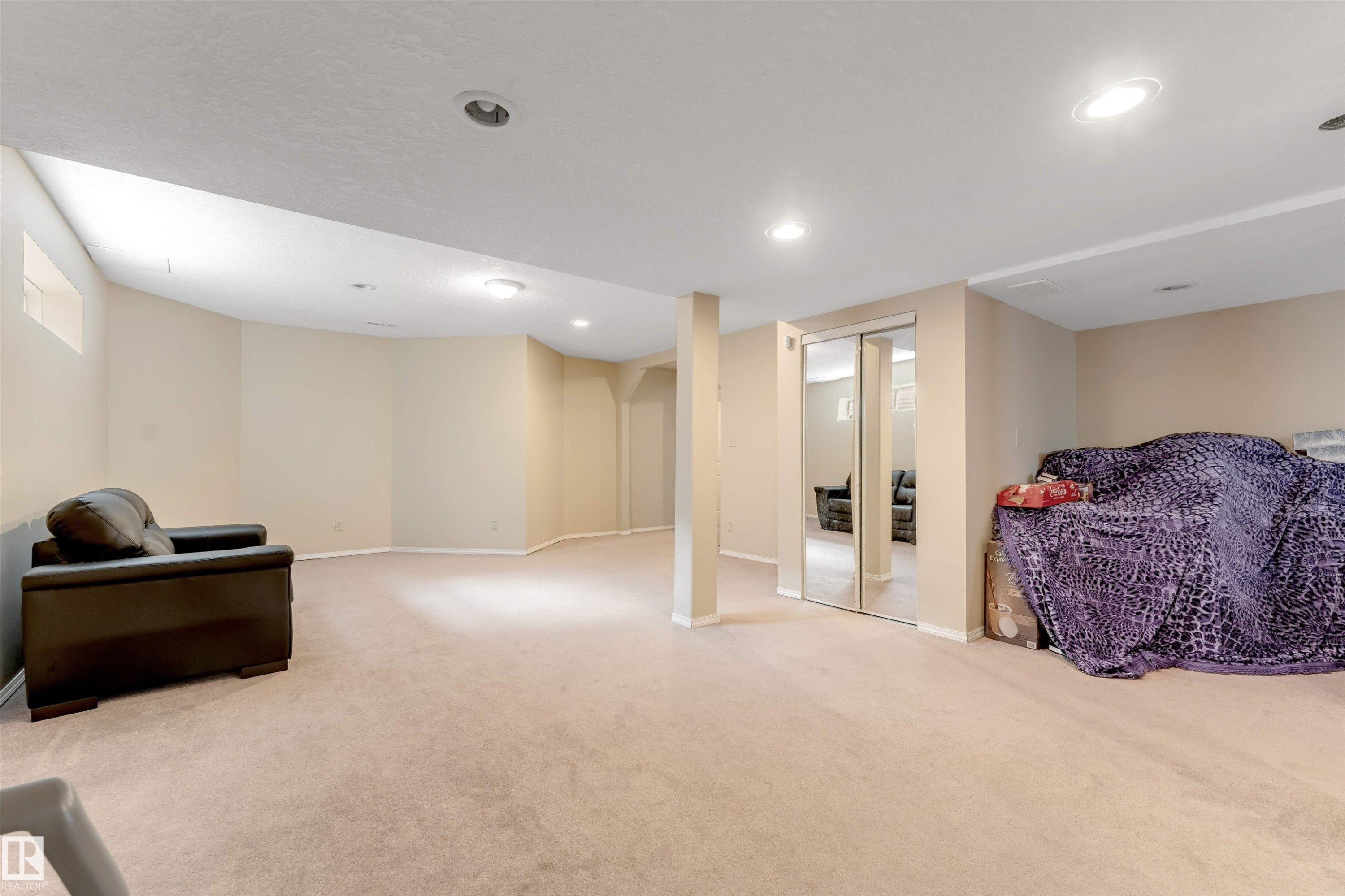 Finished basement area featuring recessed lighting, light beige carpeting, and mirrored sliding closet doors - 4465 32A Street Nw, Edmonton, AB - Indoor Photo Showing Other Room