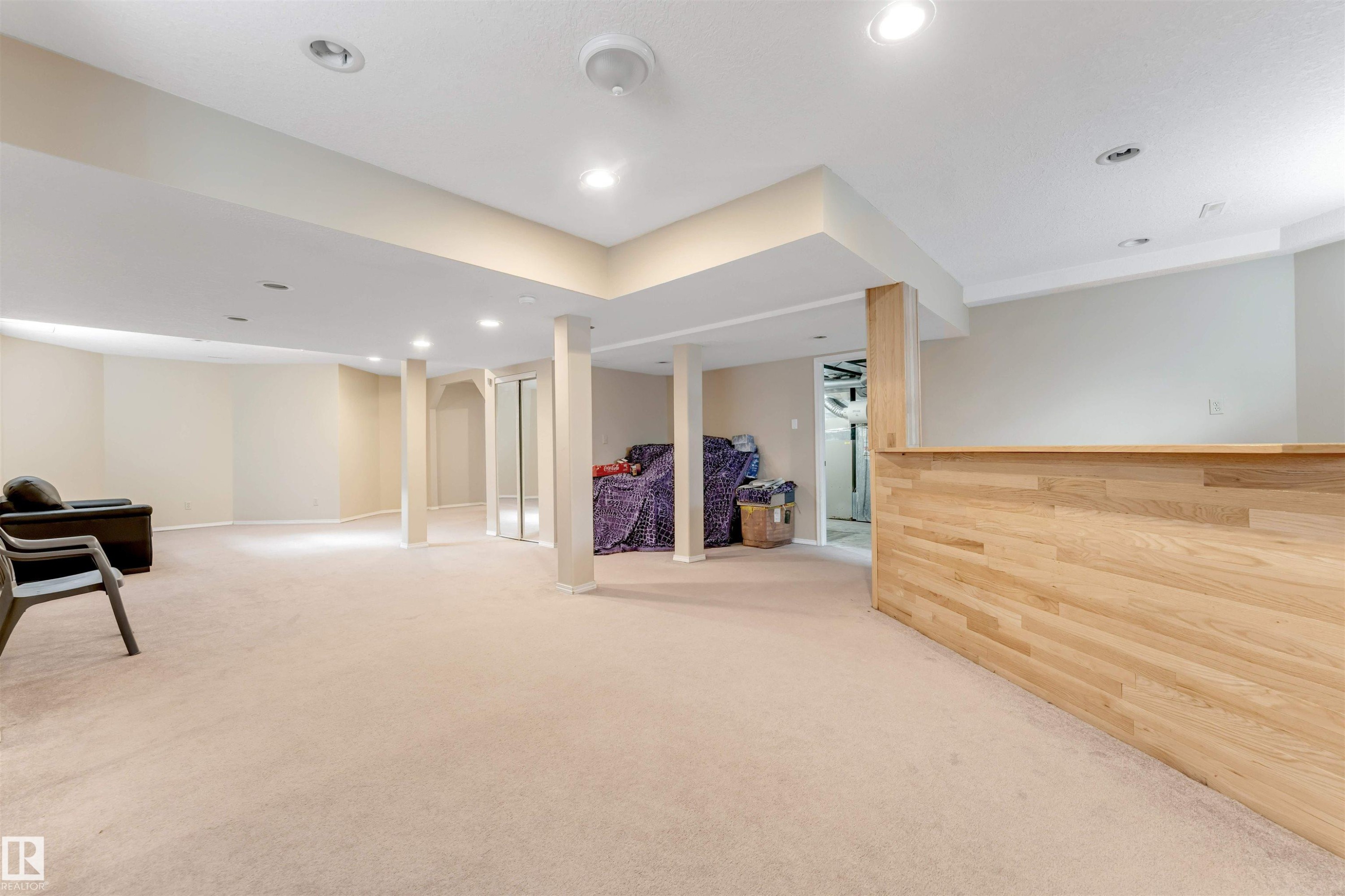 Spacious finished room featuring recessed lighting, light-toned carpeting, painted structural columns, and a built-in wood-finish half-wall - 4465 32A Street Nw, Edmonton, AB - Indoor Photo Showing Other Room