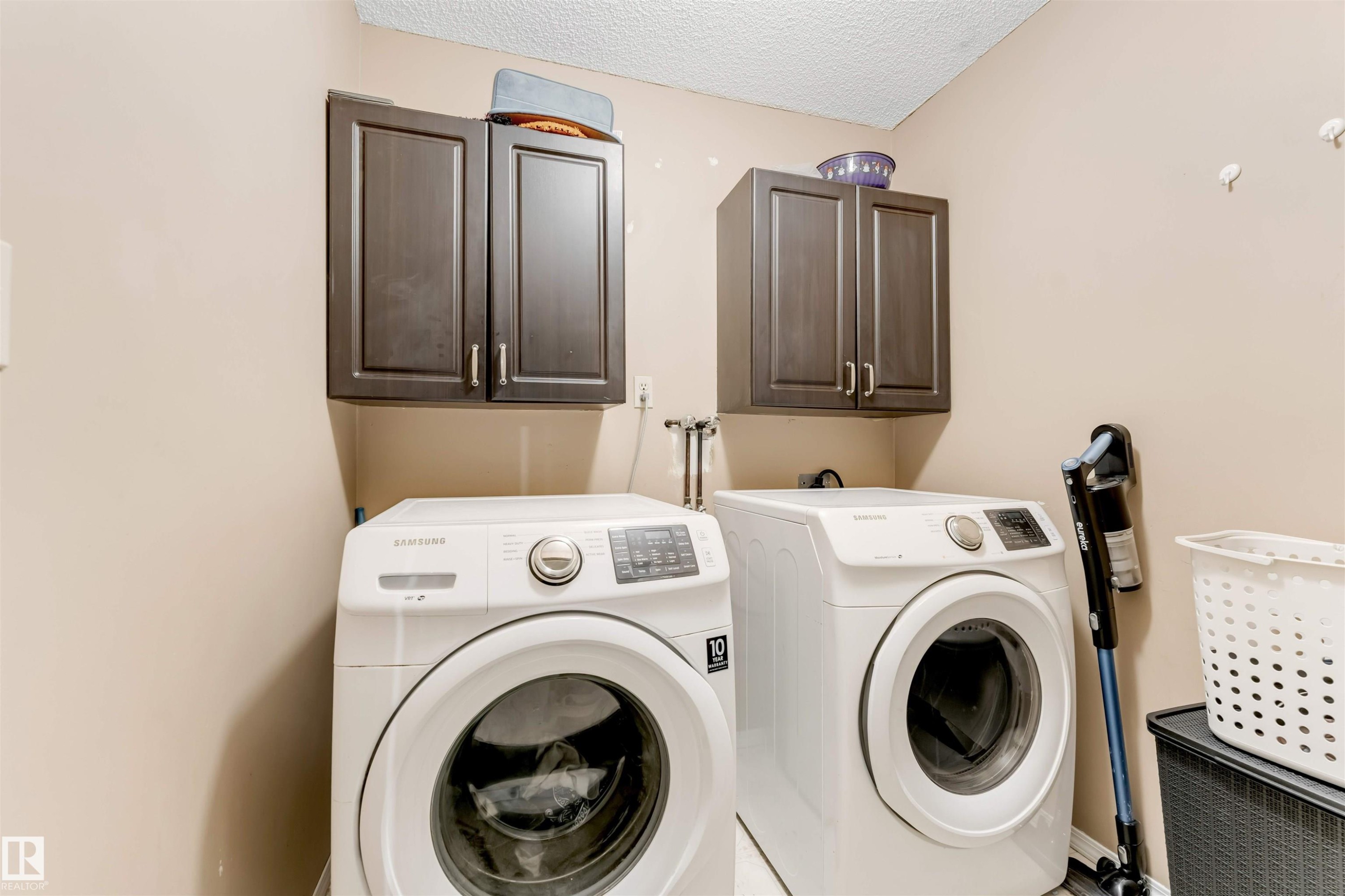 Functional laundry area featuring dual dark wood-finish cabinetry, neutral wall paint, and white textured ceiling - 4465 32A Street Nw, Edmonton, AB - Indoor Photo Showing Laundry Room