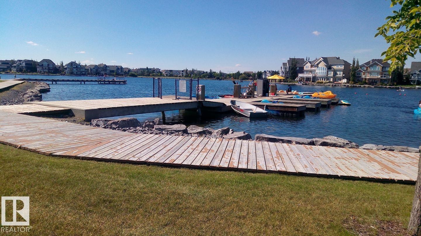 Lakeside boardwalk leading to a dock structure with adjacent residential properties - 1839 80 Street Sw, Edmonton, AB