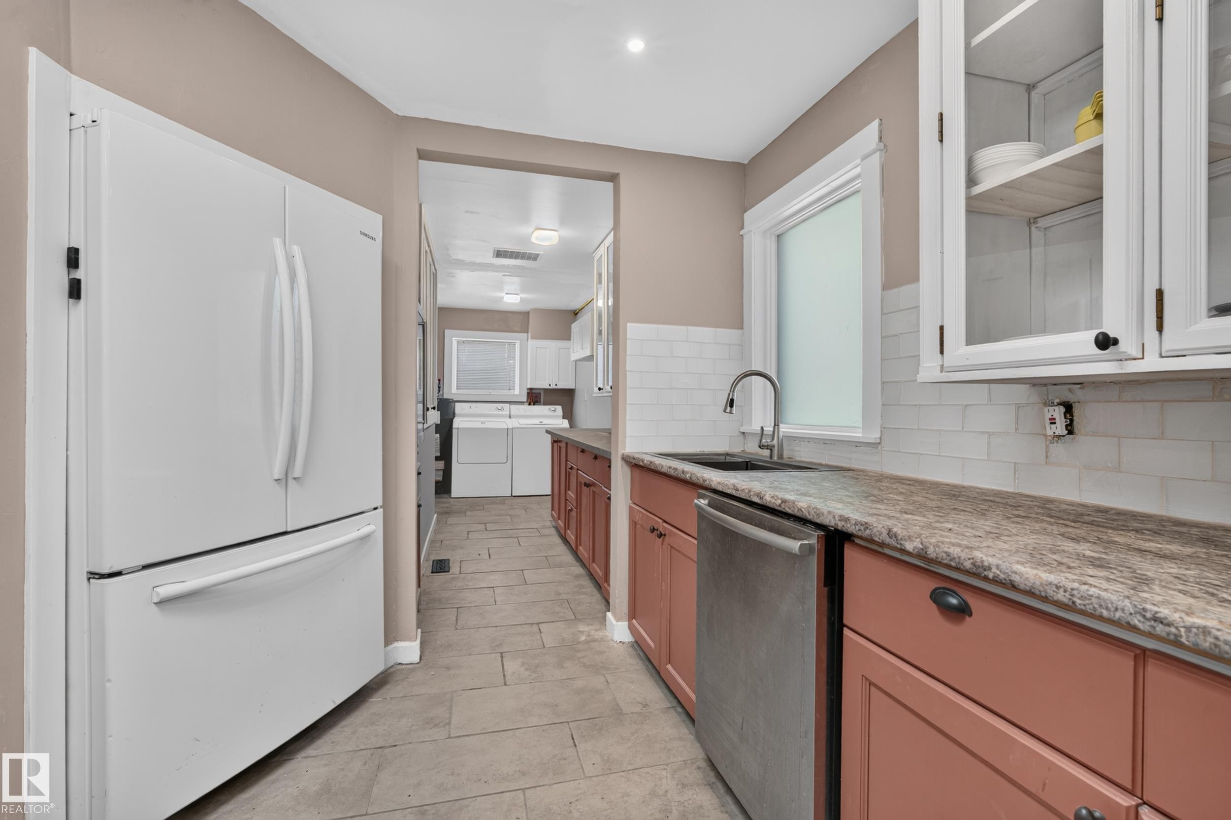 Kitchen featuring a stainless steel dishwasher, a sink with a gooseneck faucet, white subway tile backsplash, and wood-finish countertops - 11603 72 Avenue Nw, Edmonton, AB